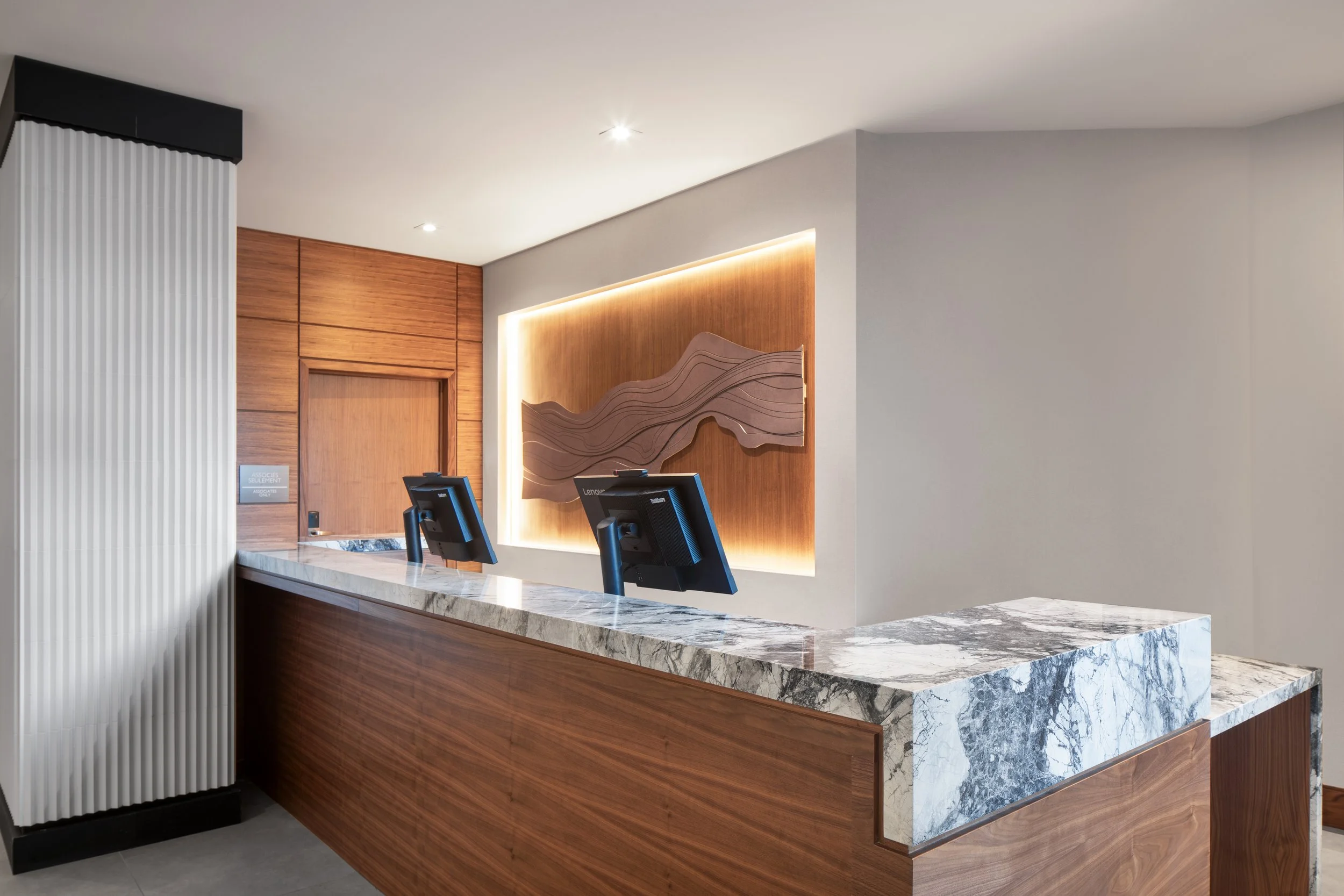 Wood and Stone hotel front desk with wood wall panelling and sculptural art