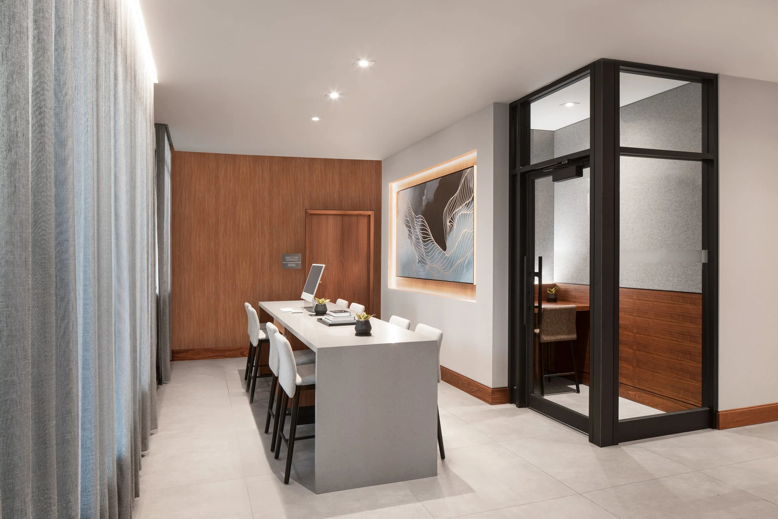 Quartz computer station and glazed phone booth surrounded by wood panelling and drapery