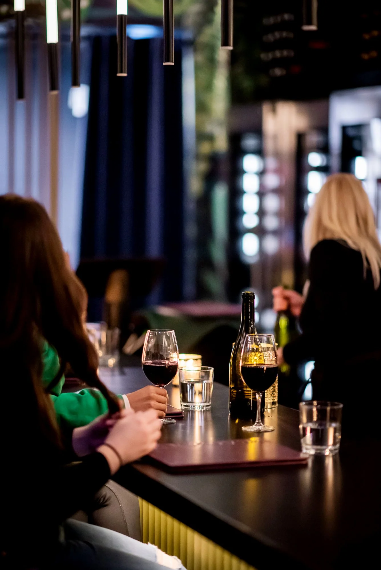 Guests sitting at the restaurant's bar with red wine