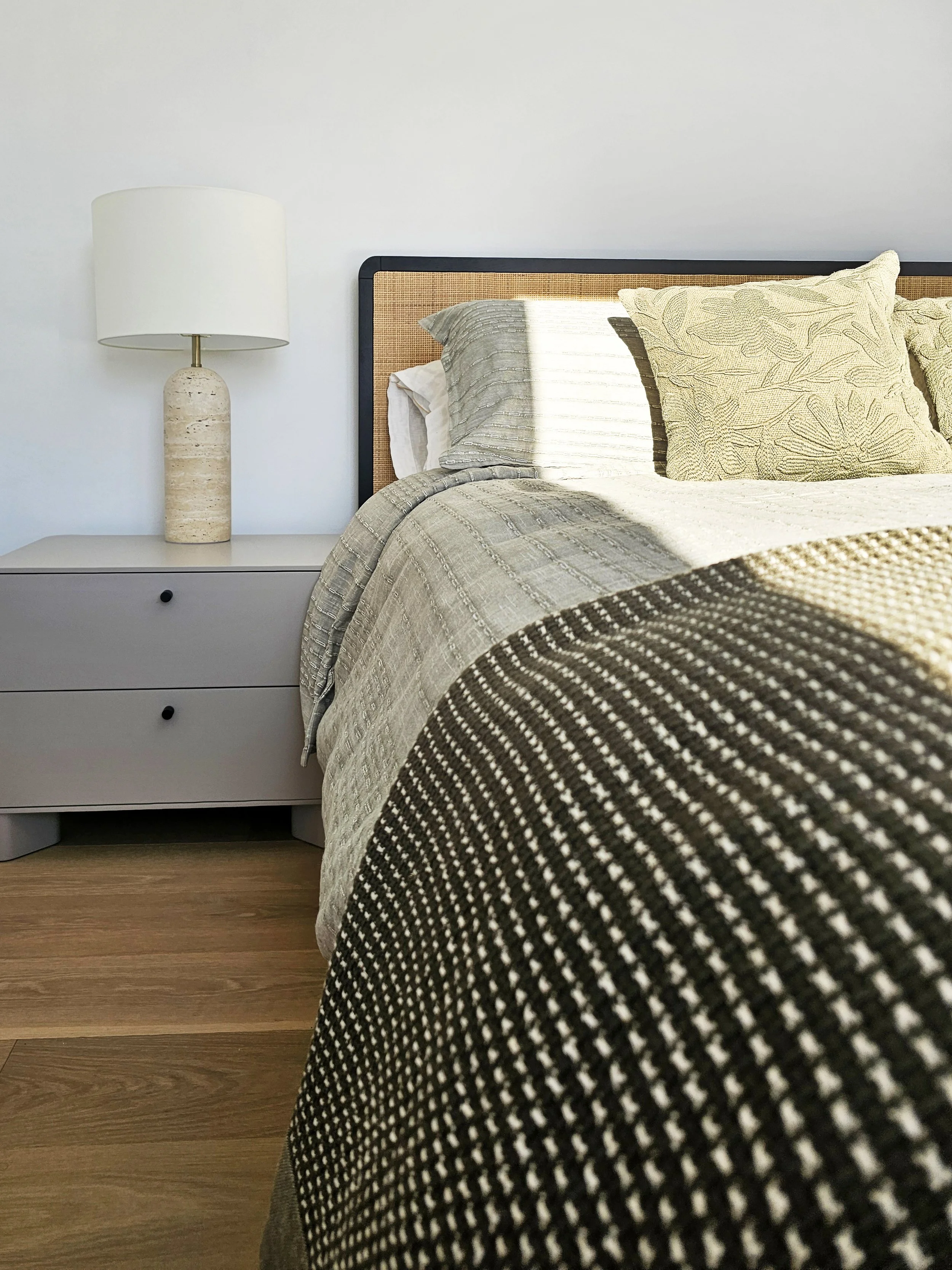 Close up bedroom image with green bedding and rattan bed