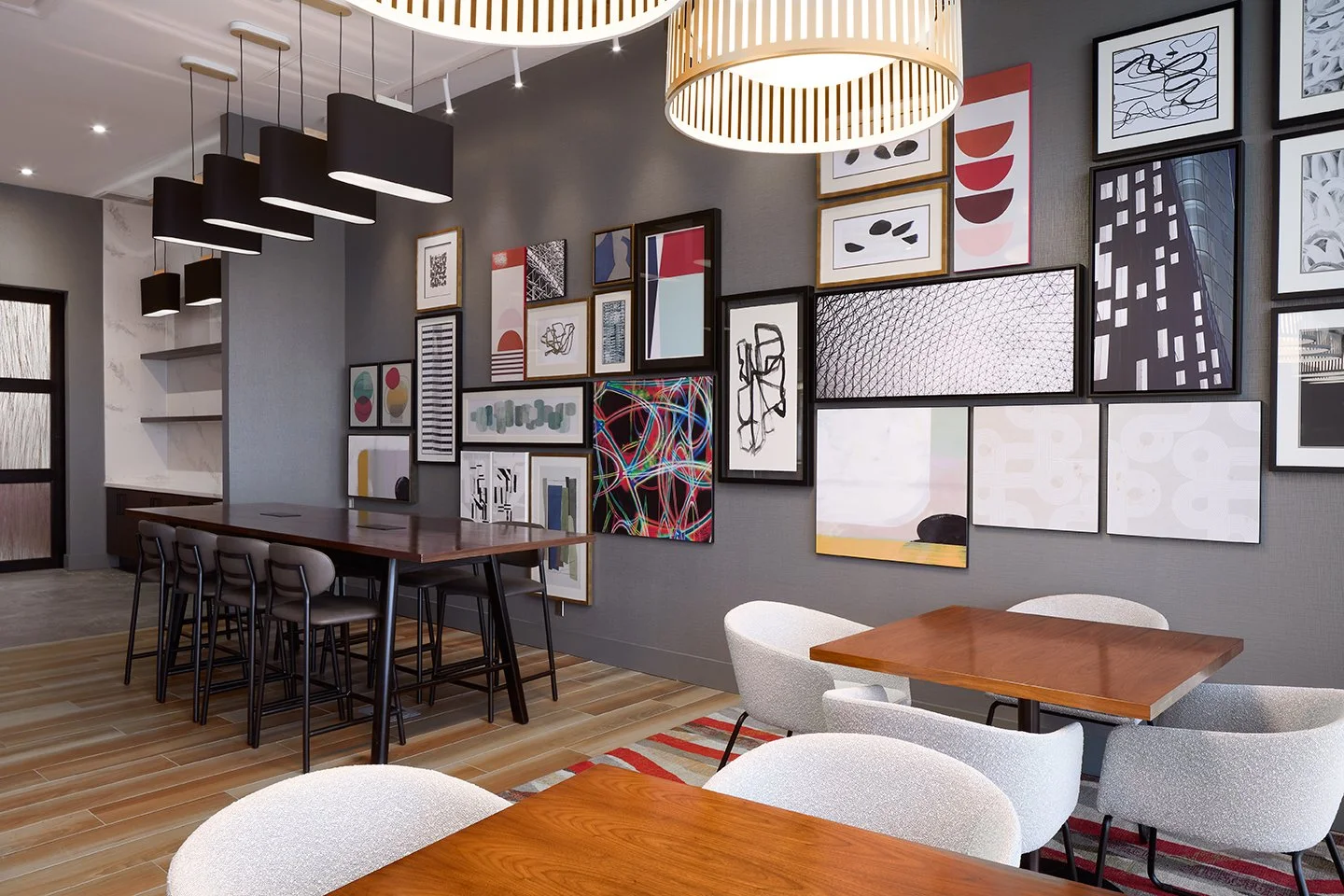 Hotel restaurant with fabric seating, wood tables, and gallery wall art with overhead pendant lighting