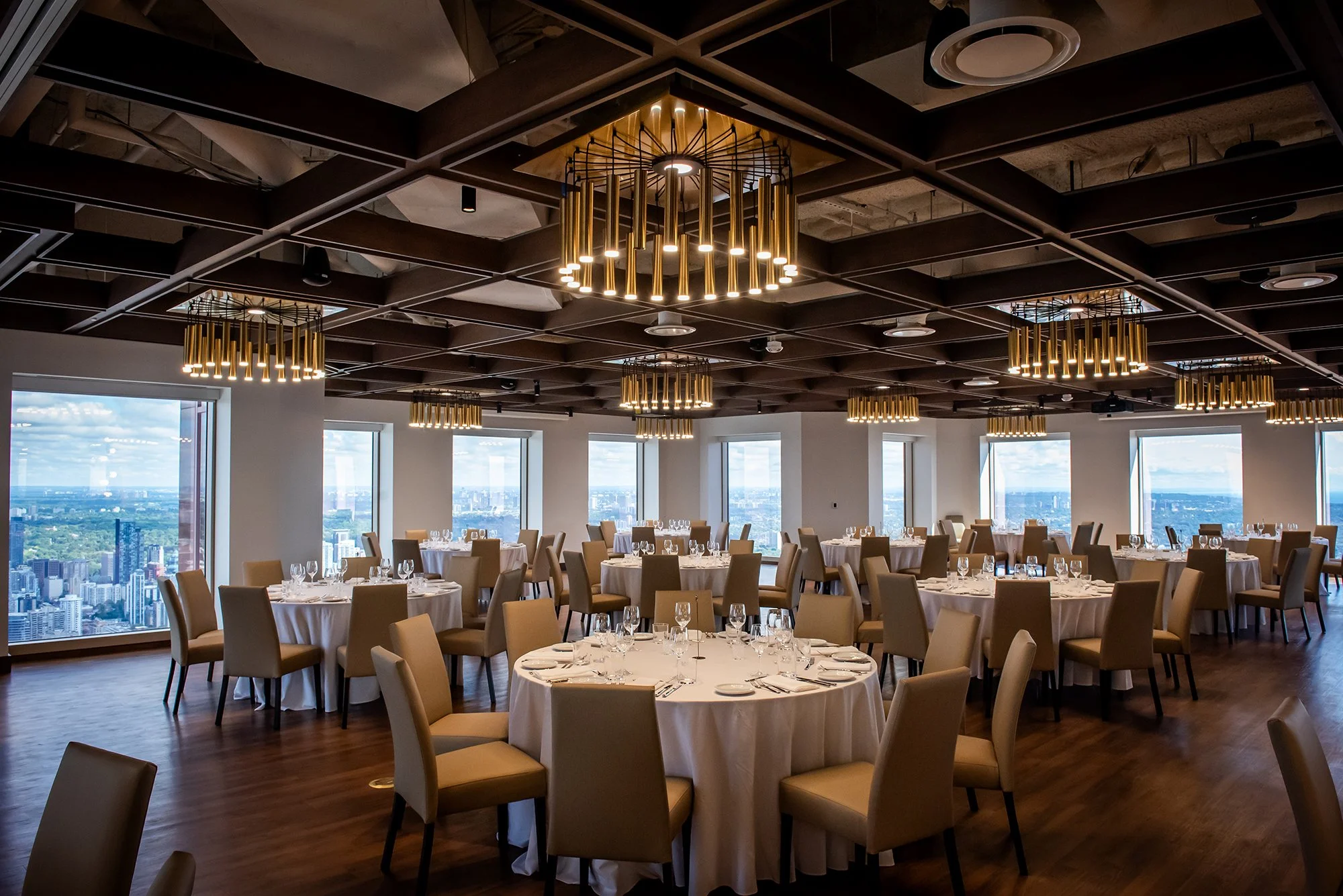 Large ballroom with windows overlooking Toronto and wood ceiling structure with brass chandeliers