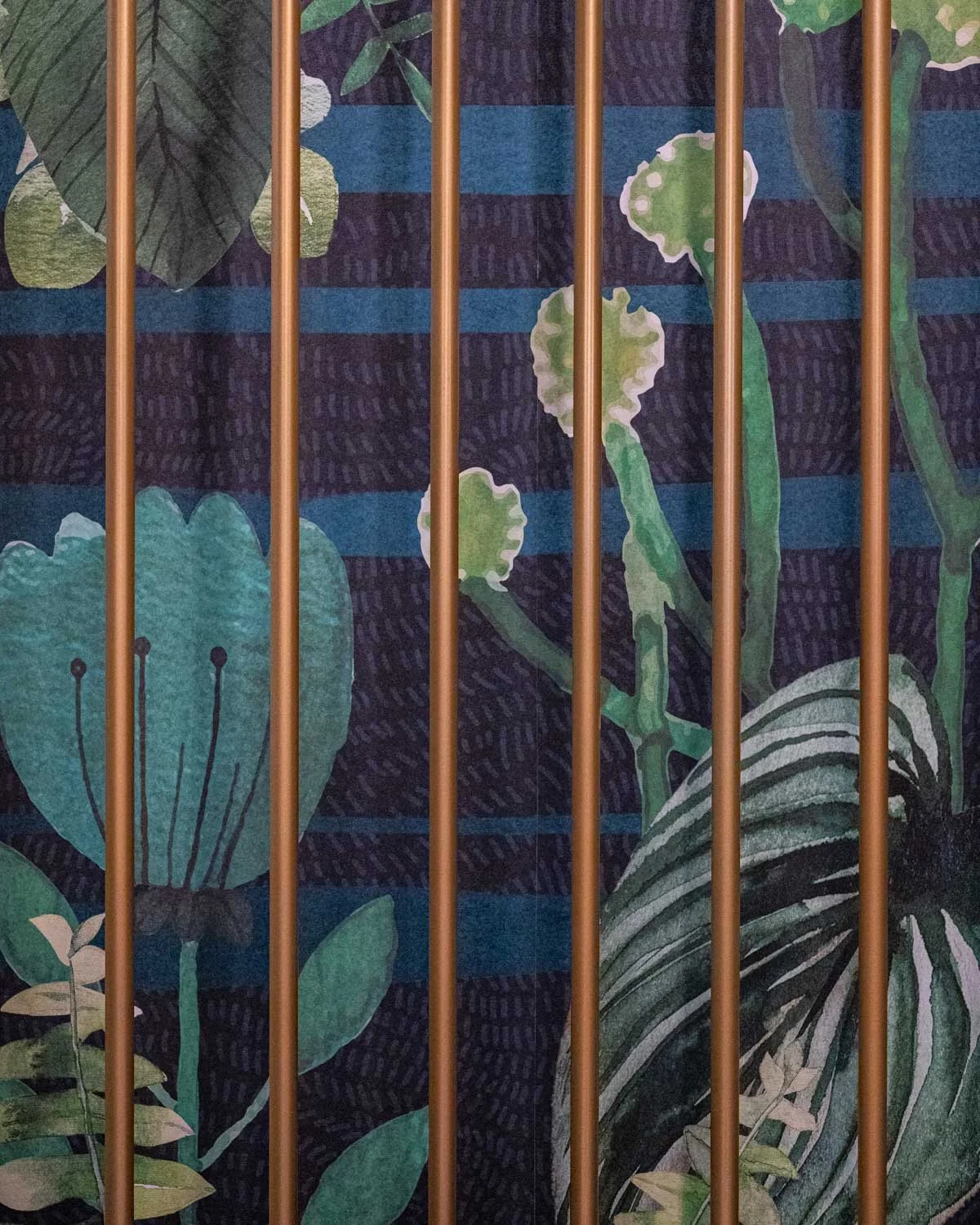 Close up of tropical plant wall mural with brass rods in front