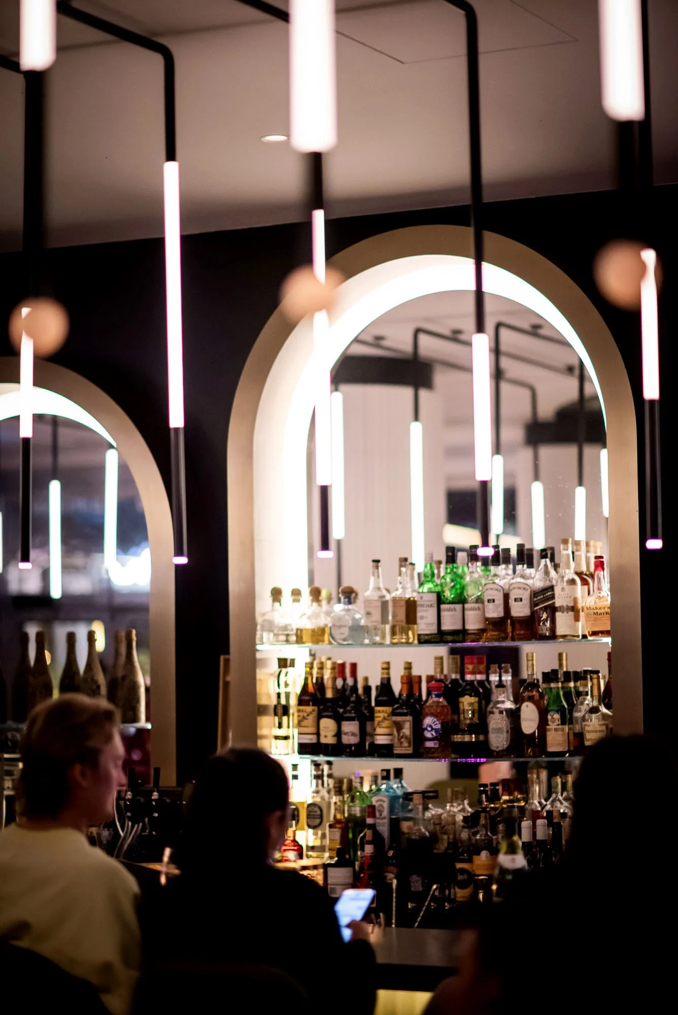 Restaurant interior liquor display at bar with lit arching structures surrounding