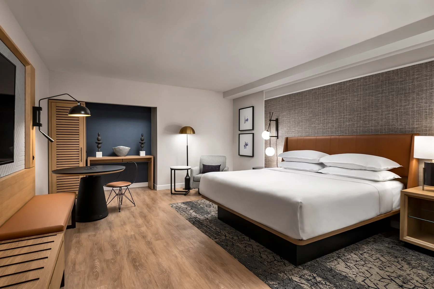 Hotel king guestroom with leather headboard, luggage bench and desk