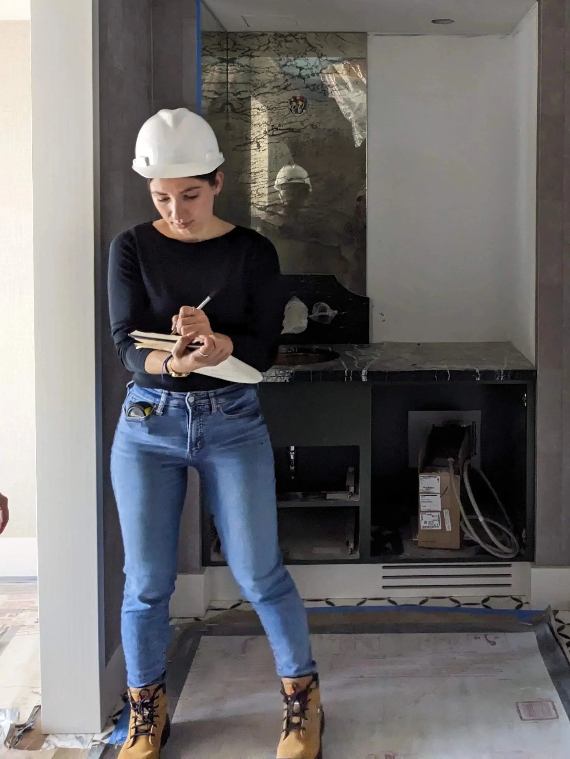 Taking notes on site with hard hat and measuring tape