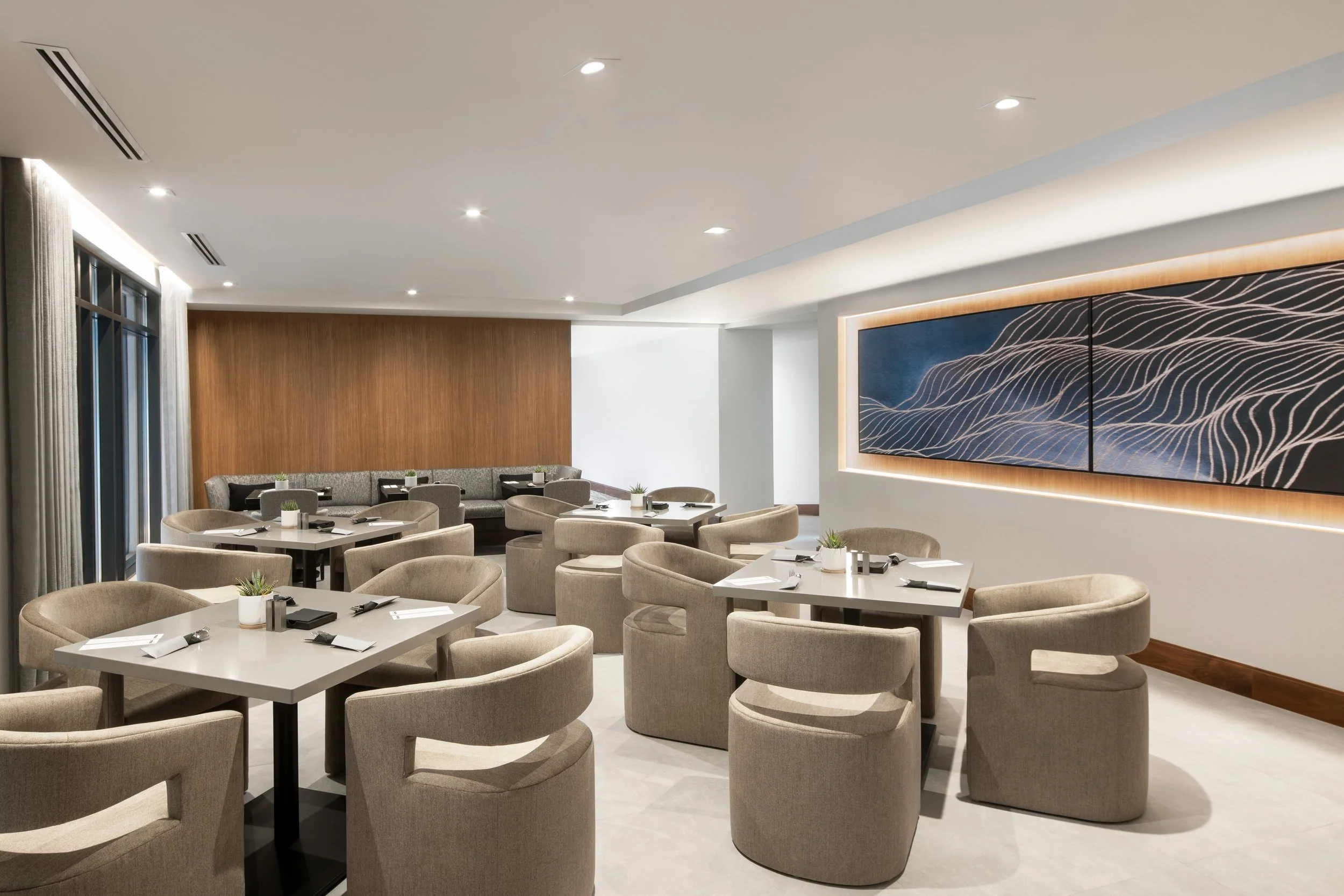 Open concept restaurant with upholstered seating surrounded by wood panelling and artwork