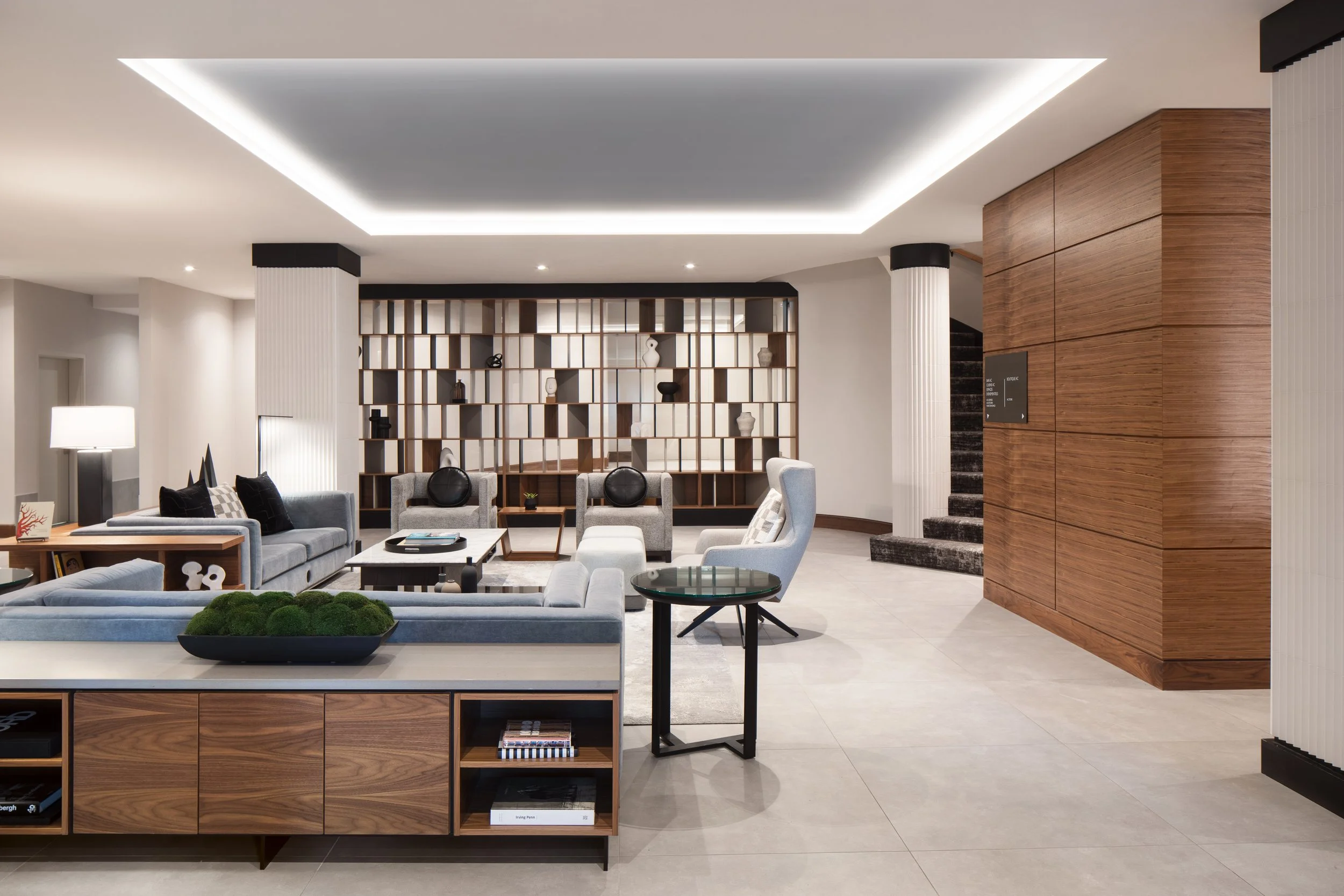 Large seating area with fabric sofas and chairs surrounded by architectural screen, columns and wood panelling
