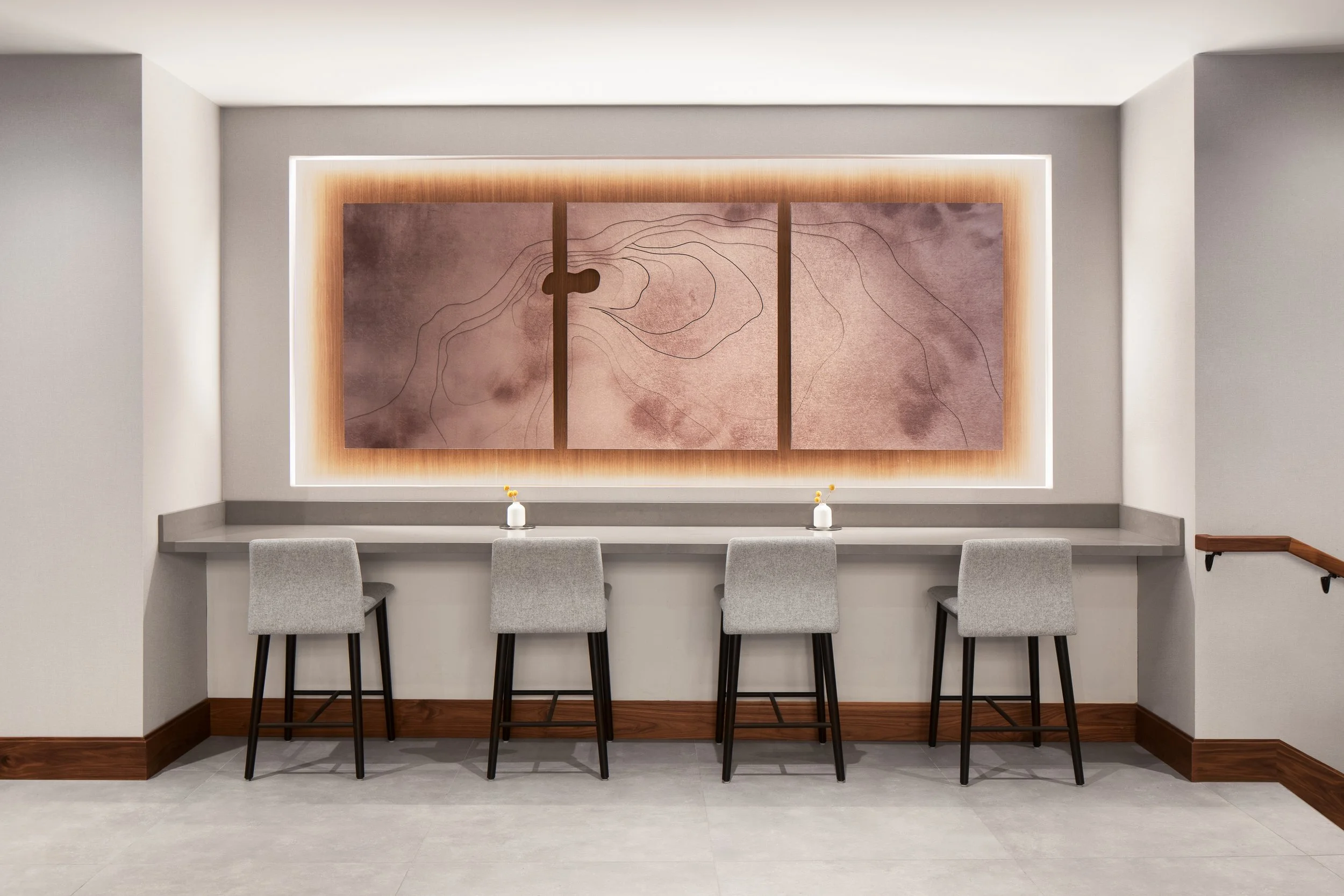 Counter at wall with upholstered stools facing 3D art installation