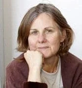 Woman with shoulder-length brown hair resting her chin on her hand, looking at the camera.