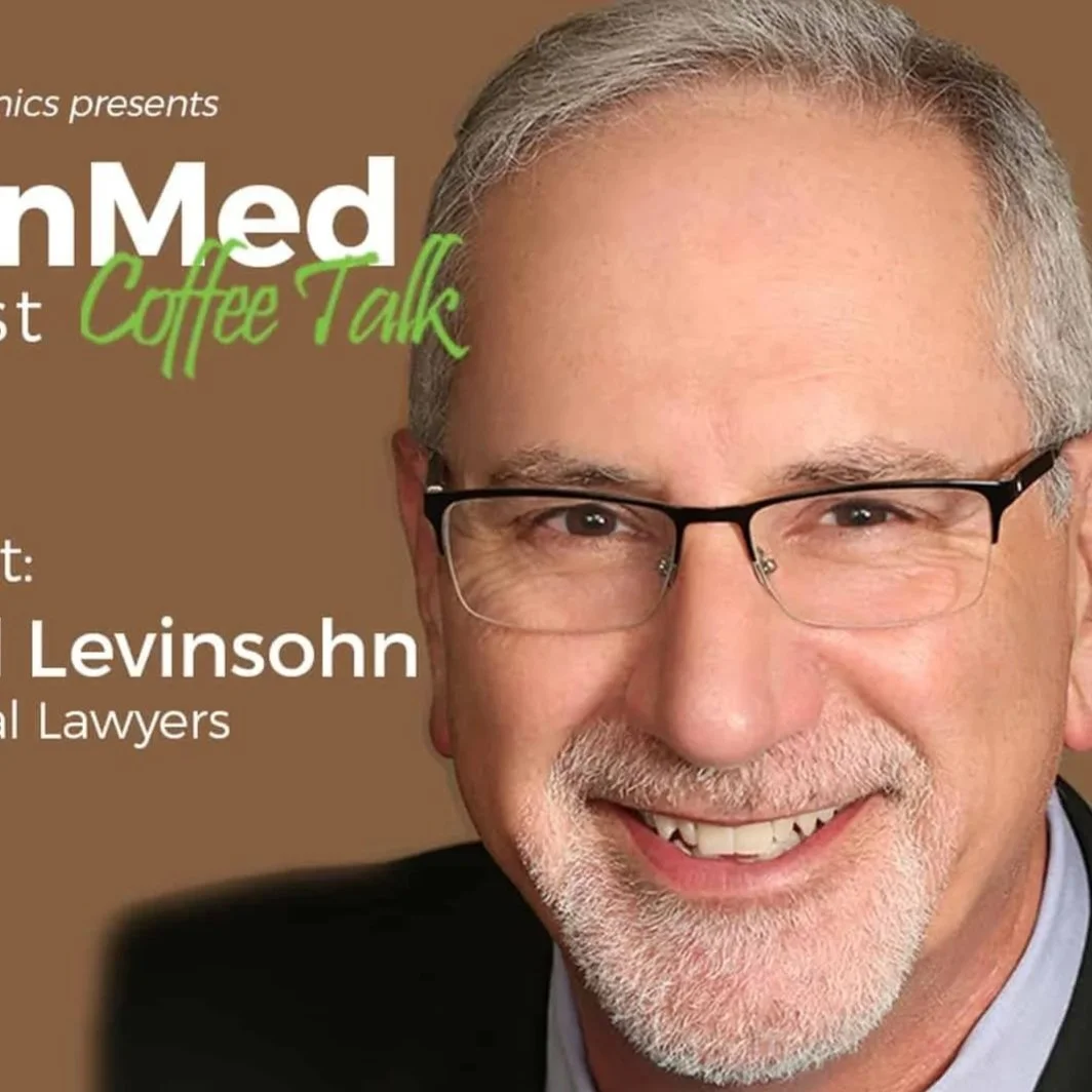 Close-up of a smiling middle-aged man with gray hair, glasses, and a beard, wearing a dark suit jacket, on a brown background with text for a coffee talk event.