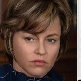 Close-up of a woman with short brown hair and a serious expression
