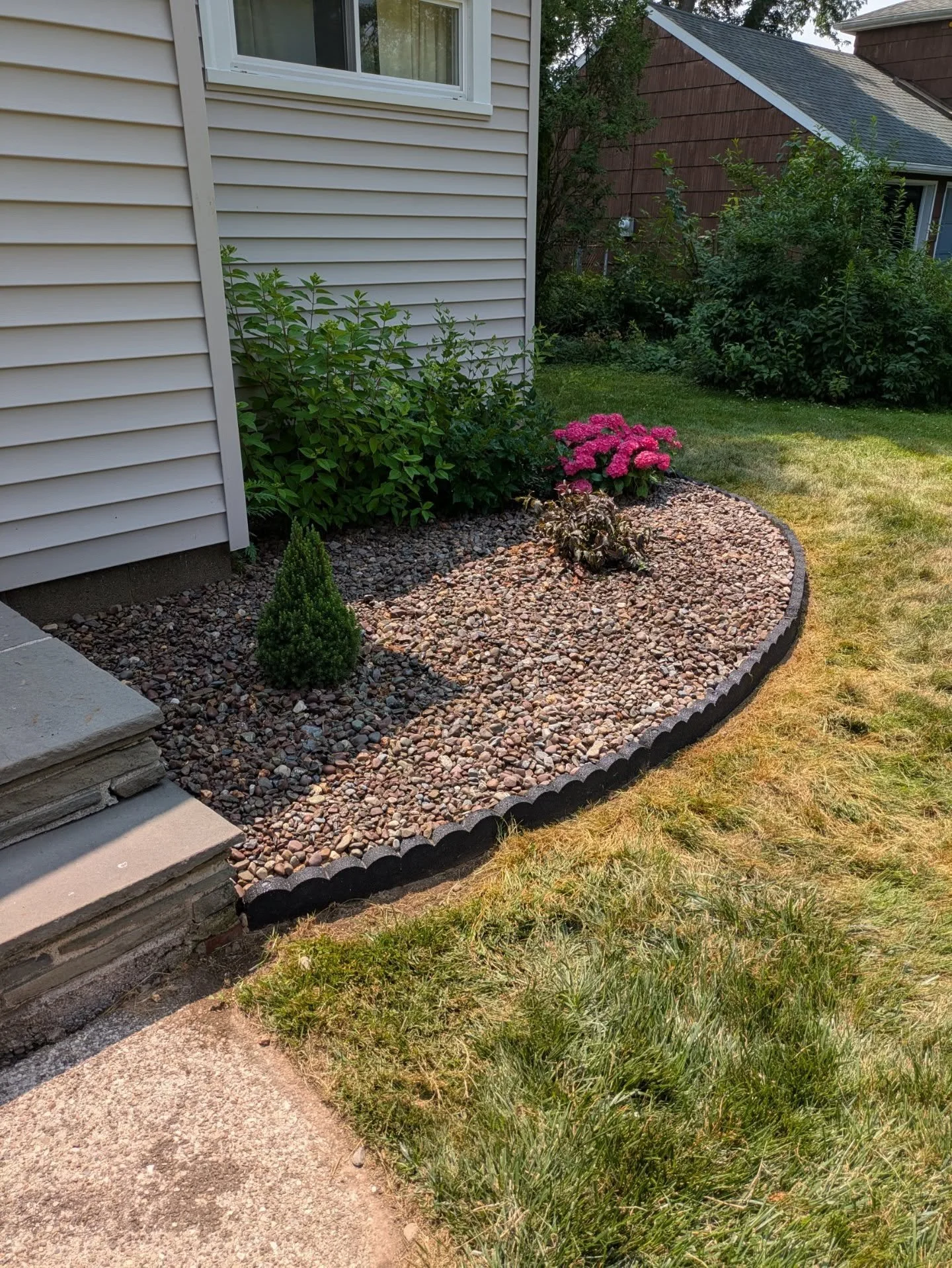 Before &amp; after photos of one of our landscaping projects in mid July. This project included digging out and adding a new border to contain the landscape and rock. Planting of two Dwarf Alberta Spruce, and one Wine Weigela. As well as spreading ha