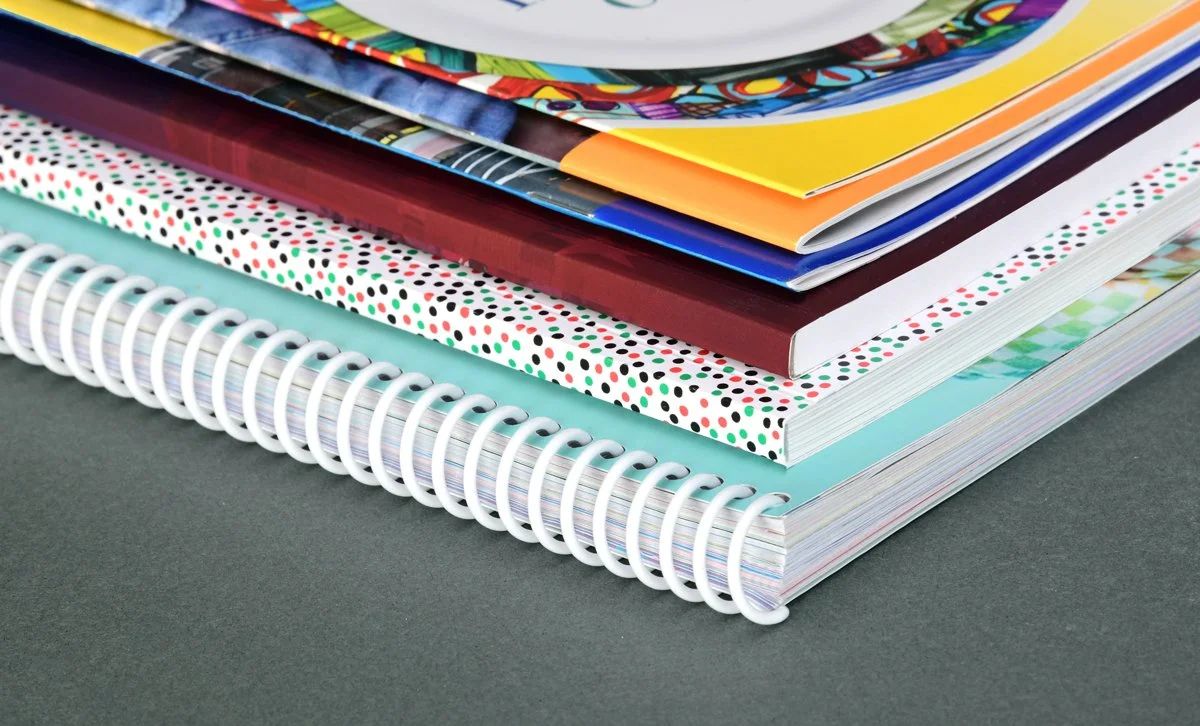 Stack of colorful notebooks and magazines on a dark surface