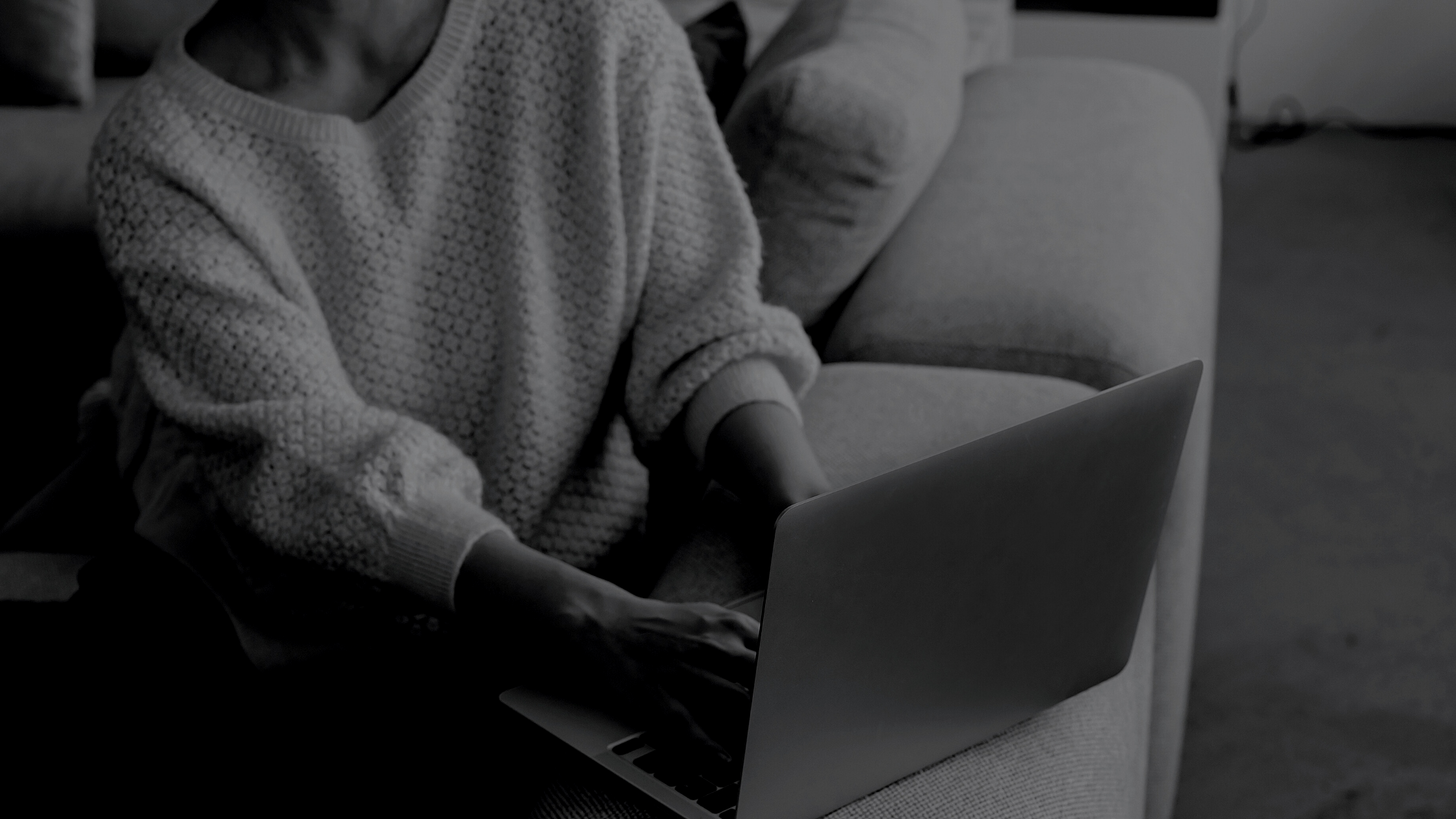 A person sitting on a couch, working on a laptop in a cozy living room.