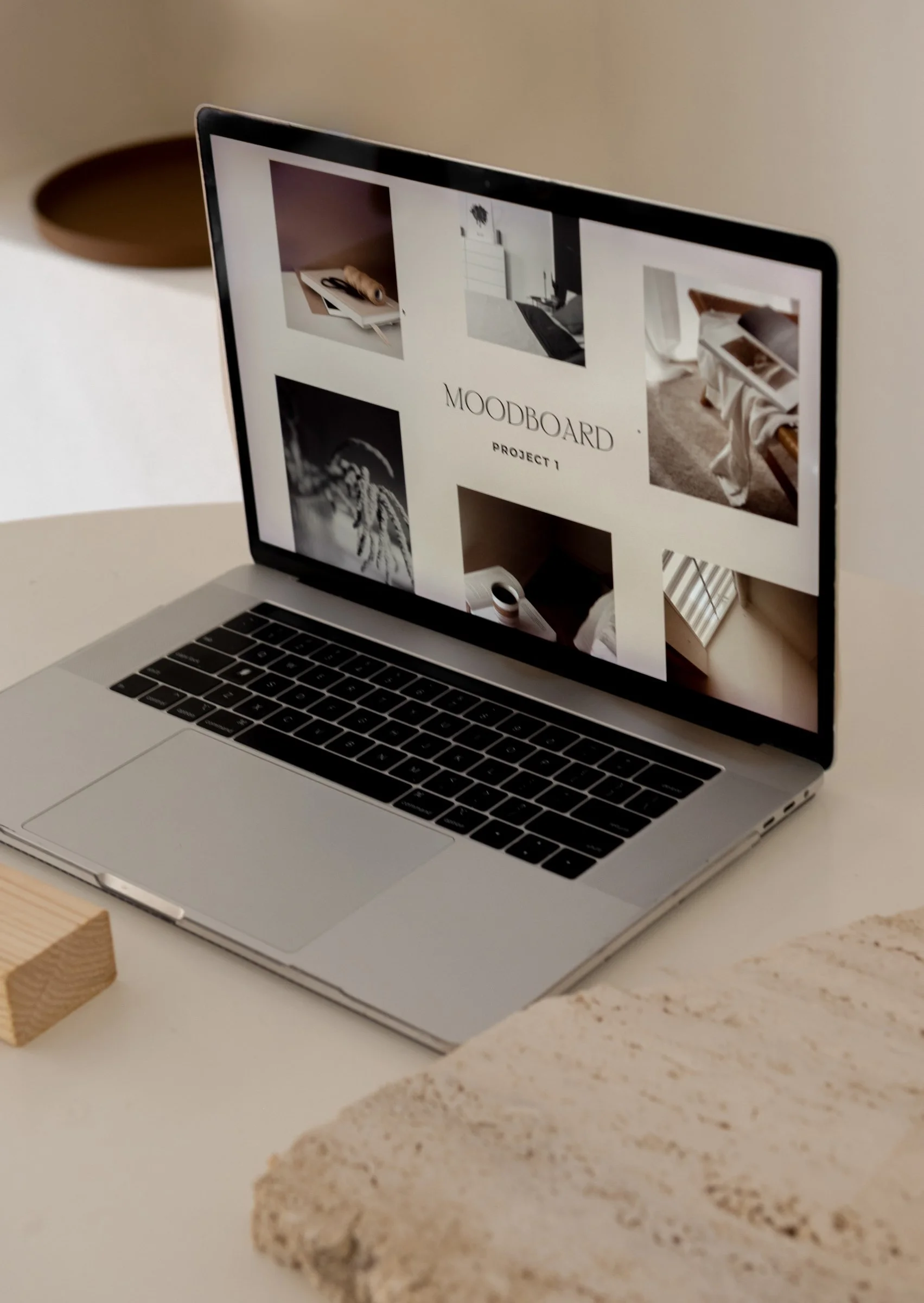 A laptop on a white surface displaying a moodboard project with images of art, interior design, and textiles.