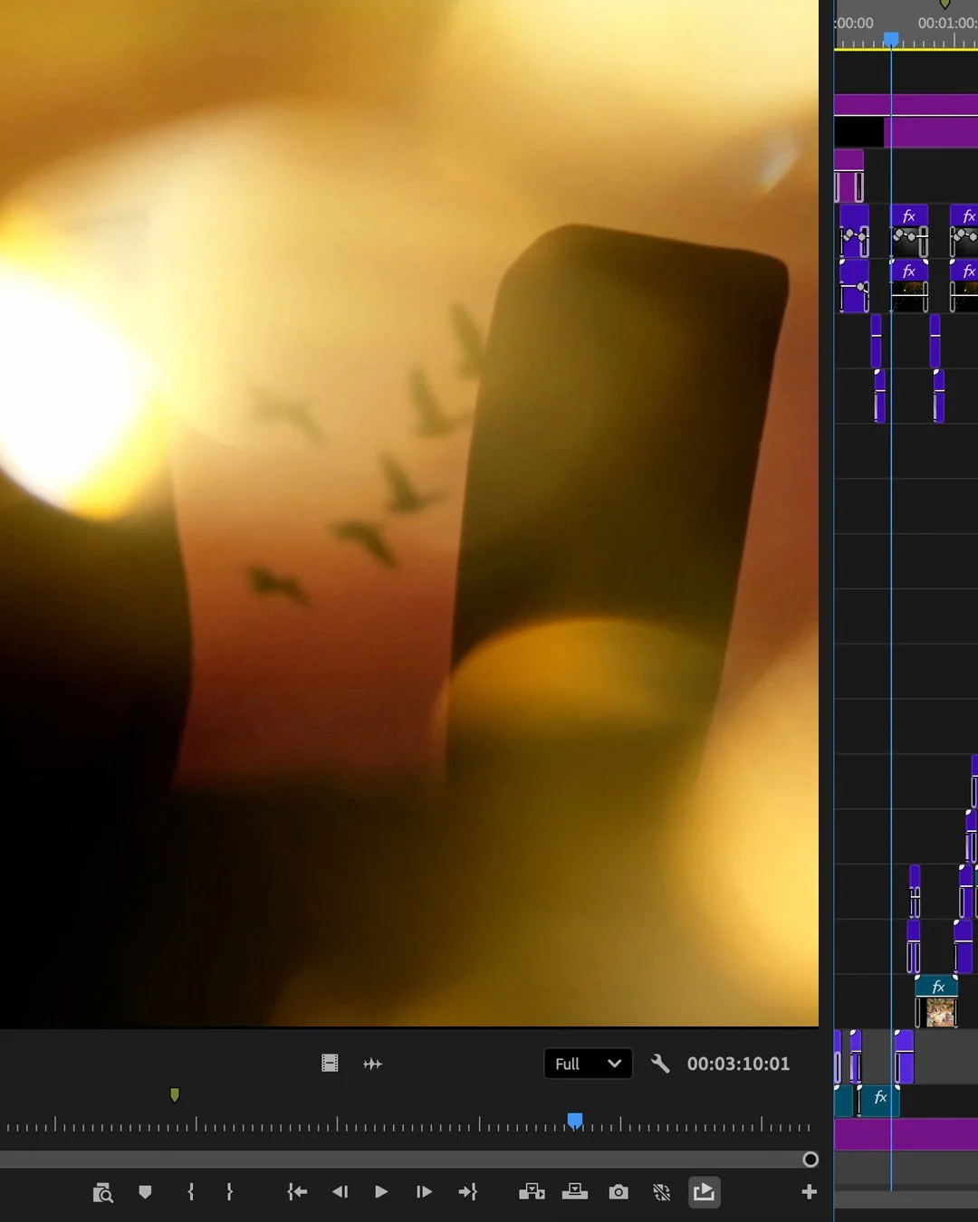 Blurry close-up of a video editing timeline with purple and blue clips, and an abstract background with warm hues and dark silhouettes.