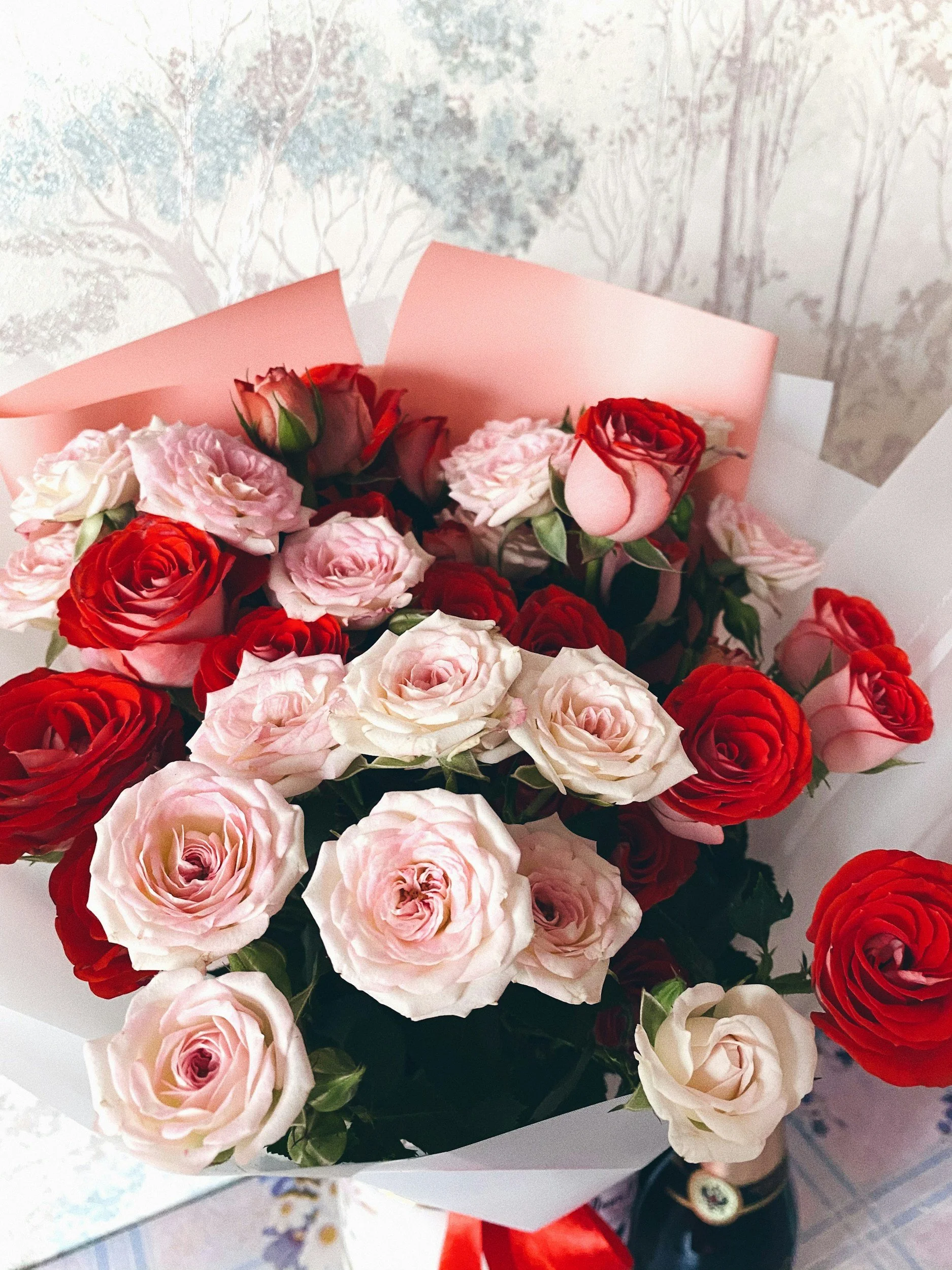 Bouquet of pink and red roses wrapped in pink and white paper.