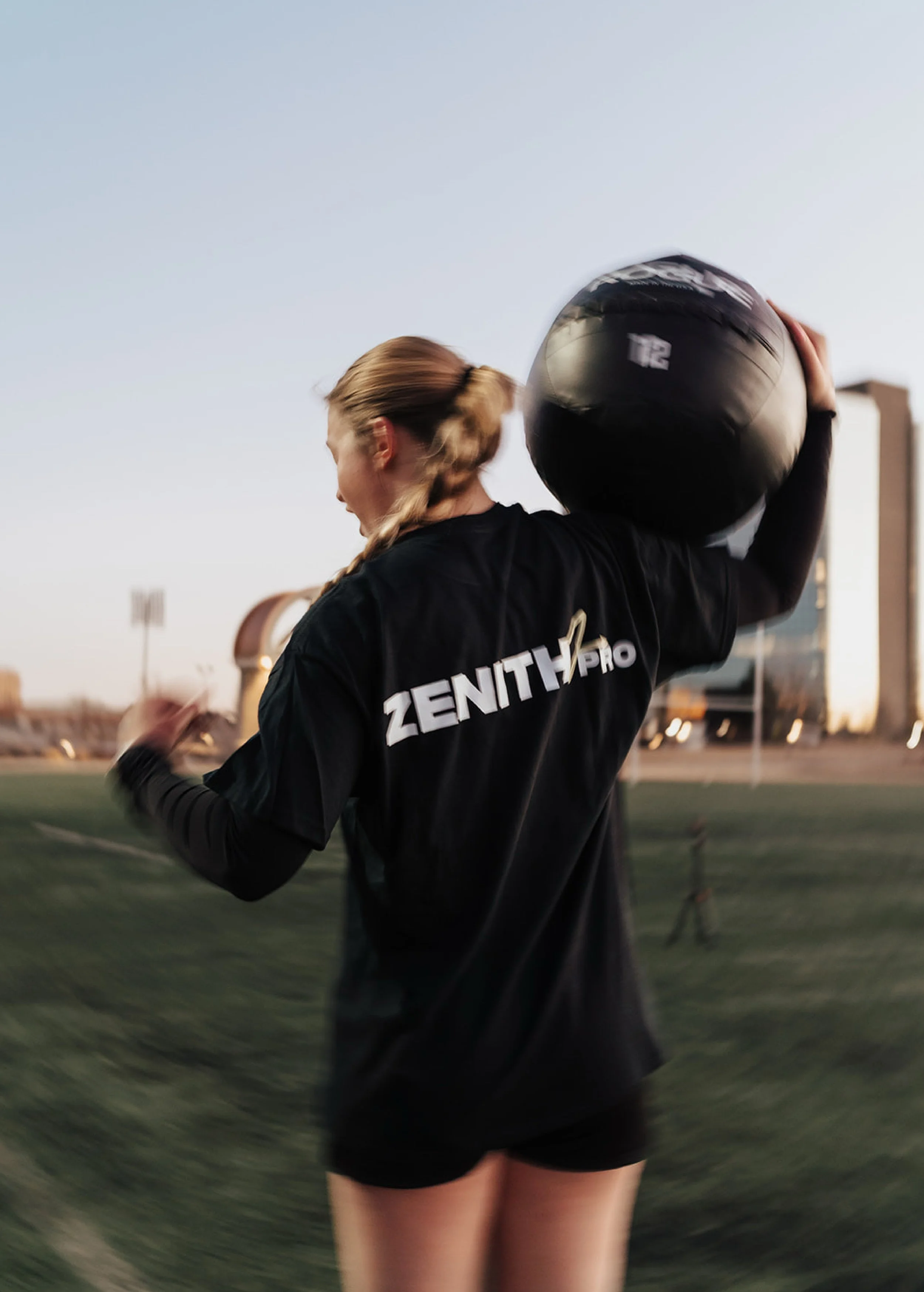 woman holding medicine ball posing with branded merch on long sleeve t shirt