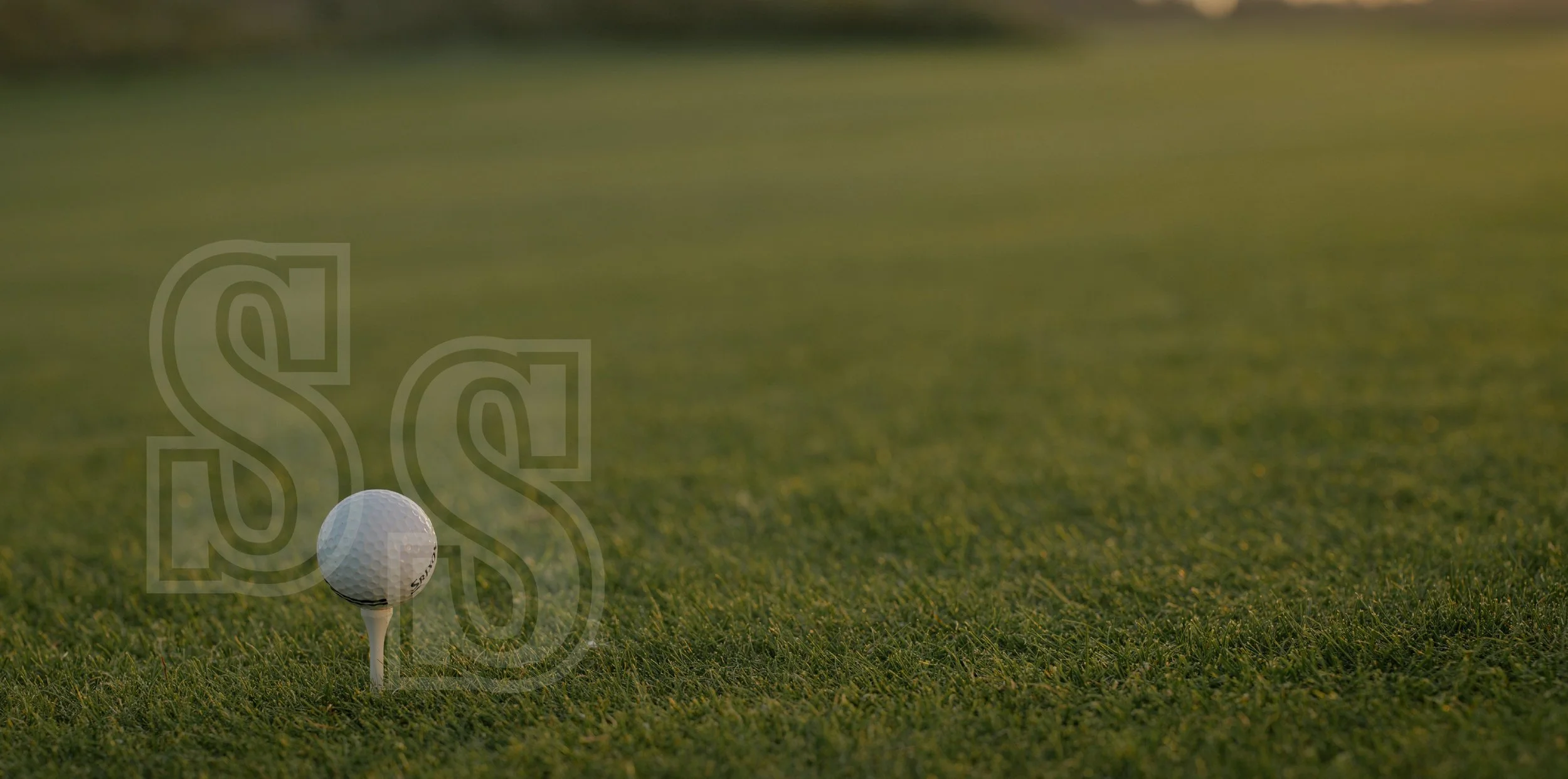 A golf ball on a tee on a grassy golf course, with a blurred background.