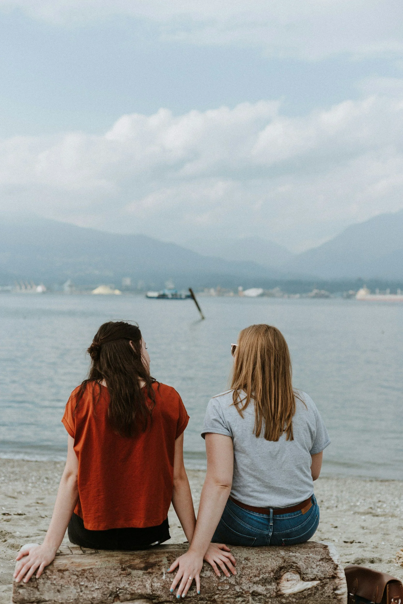Mothers sitting by the beach discussing postpartum, representing shared parenting support during postpartum and highlighting the importance of ppd therapy in Houston, TX and working with a therapist specializing in postpartum in Houston, TX.
