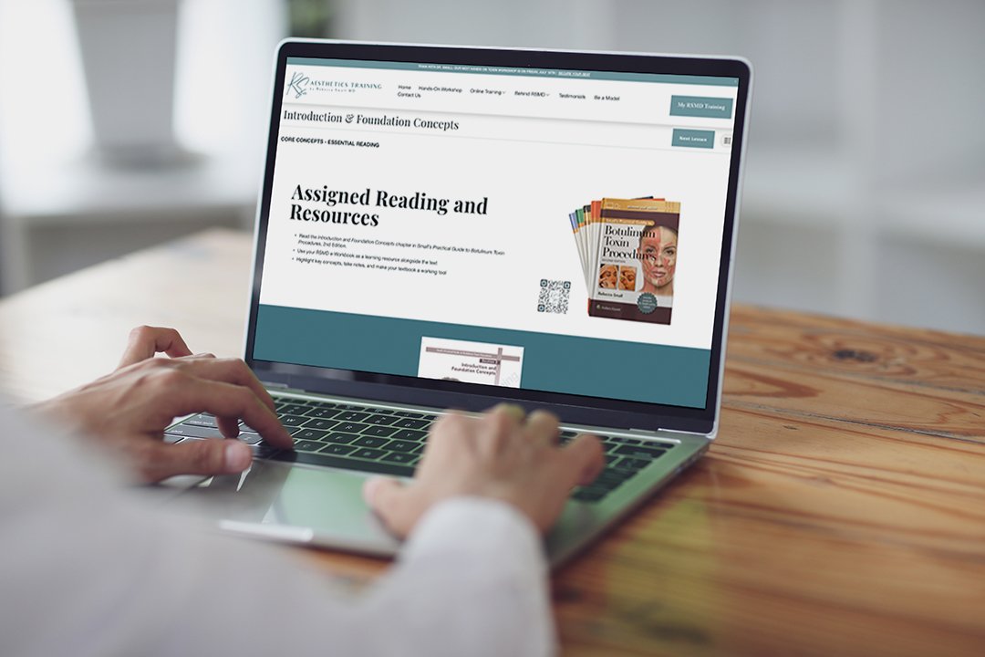 Person browsing an educational webpage on a laptop, displaying a section titled 'Assigned Reading and Resources' about foundation concepts and related books.