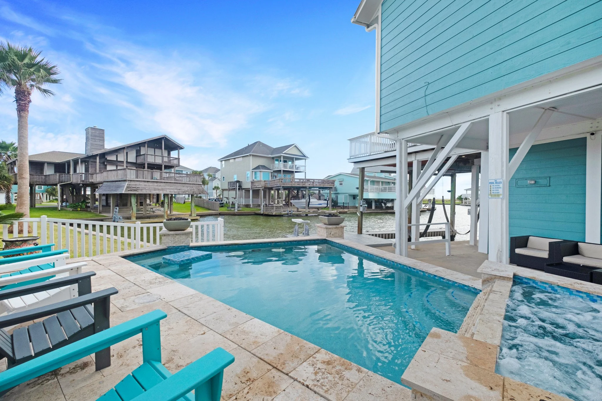 Pool in front of colorful beach houses on a waterway with a blue sky and some clouds.