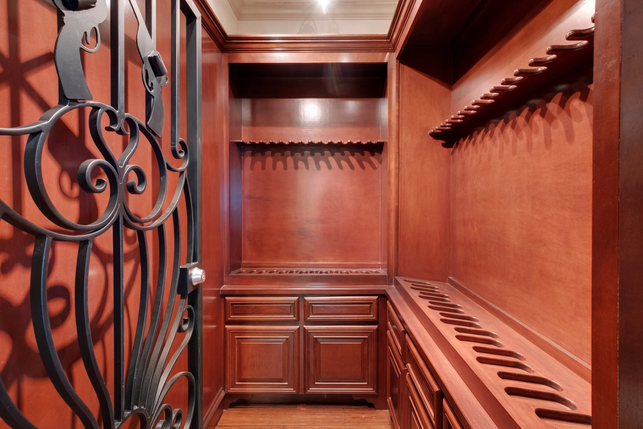 Empty wooden wine or liquor cabinet with hooks and storage drawers inside.