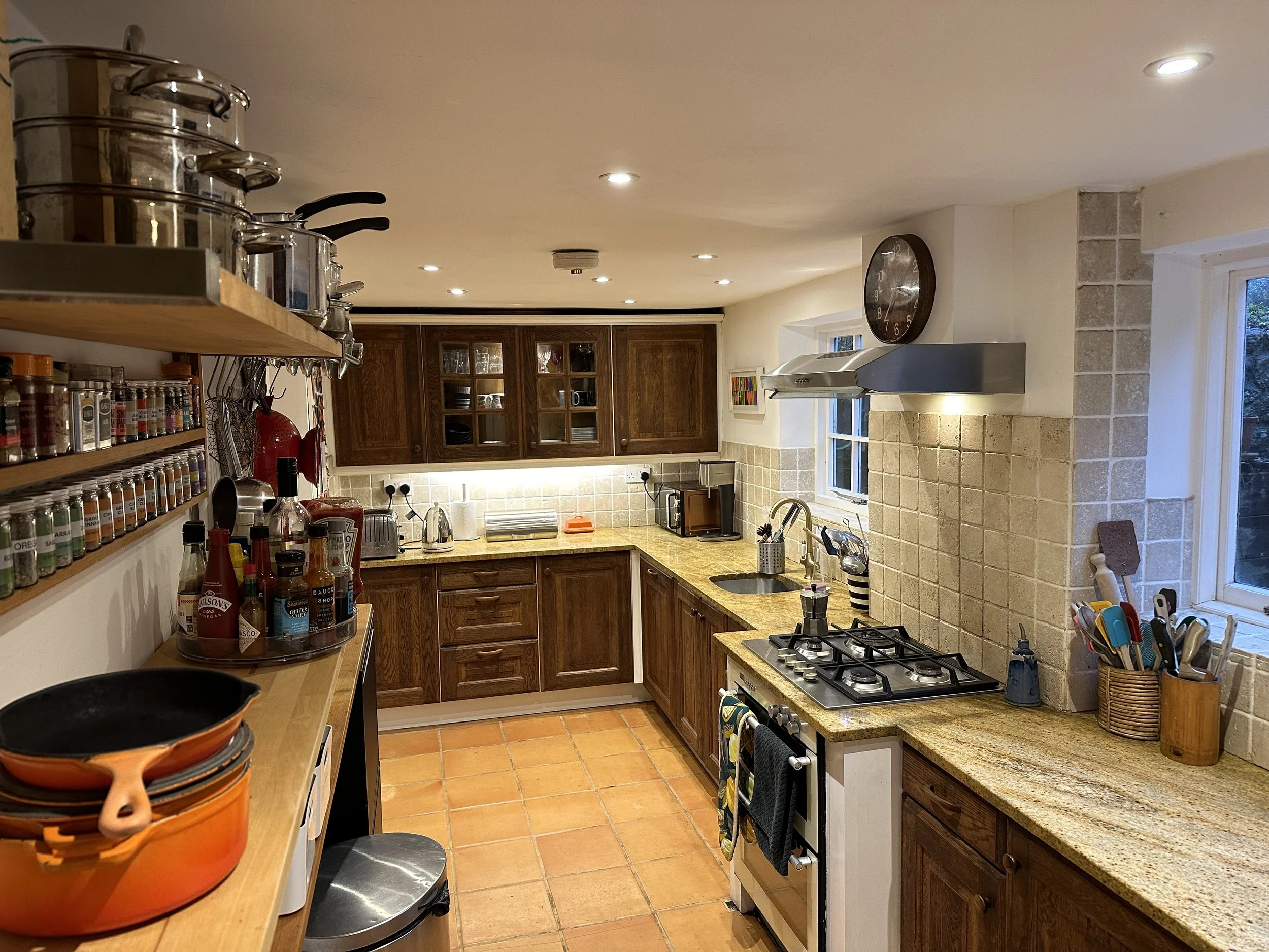Kitchen with wooden cabinets, granite countertops, a gas stove, a window, and various kitchen utensils and spices.