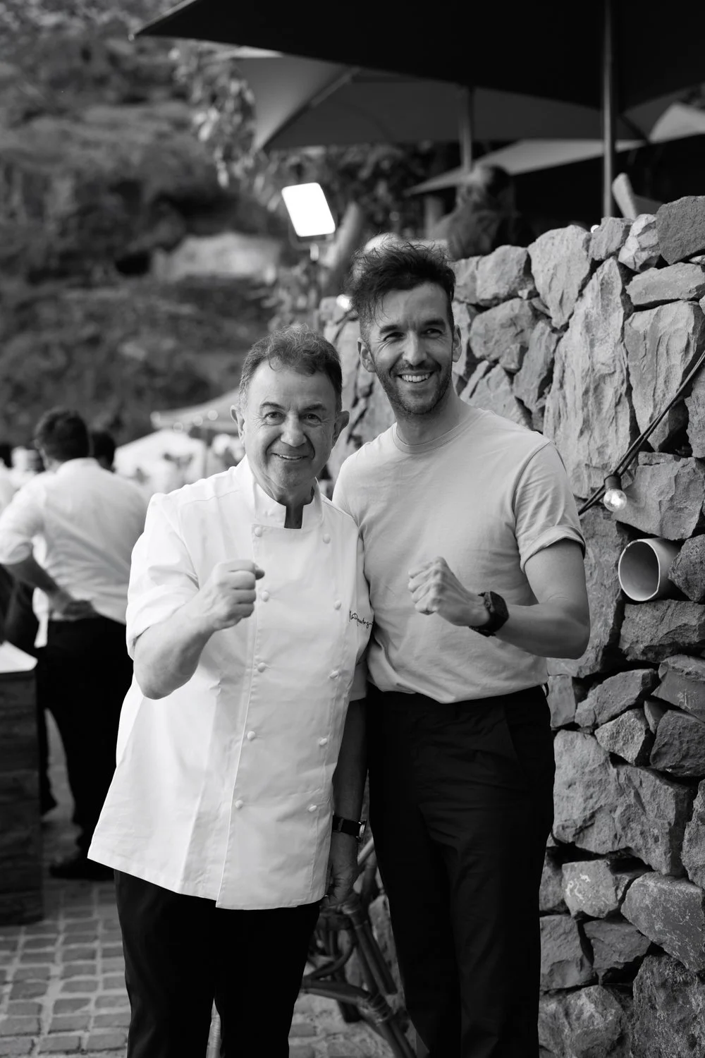 El fotógrafo David Fernández y el chef Martín Berasategui posando divertidos durante una boda en el Hotel Abama, Tenerife. Ejemplo de gastronomía de lujo y catering de alto nivel para bodas exclusivas.