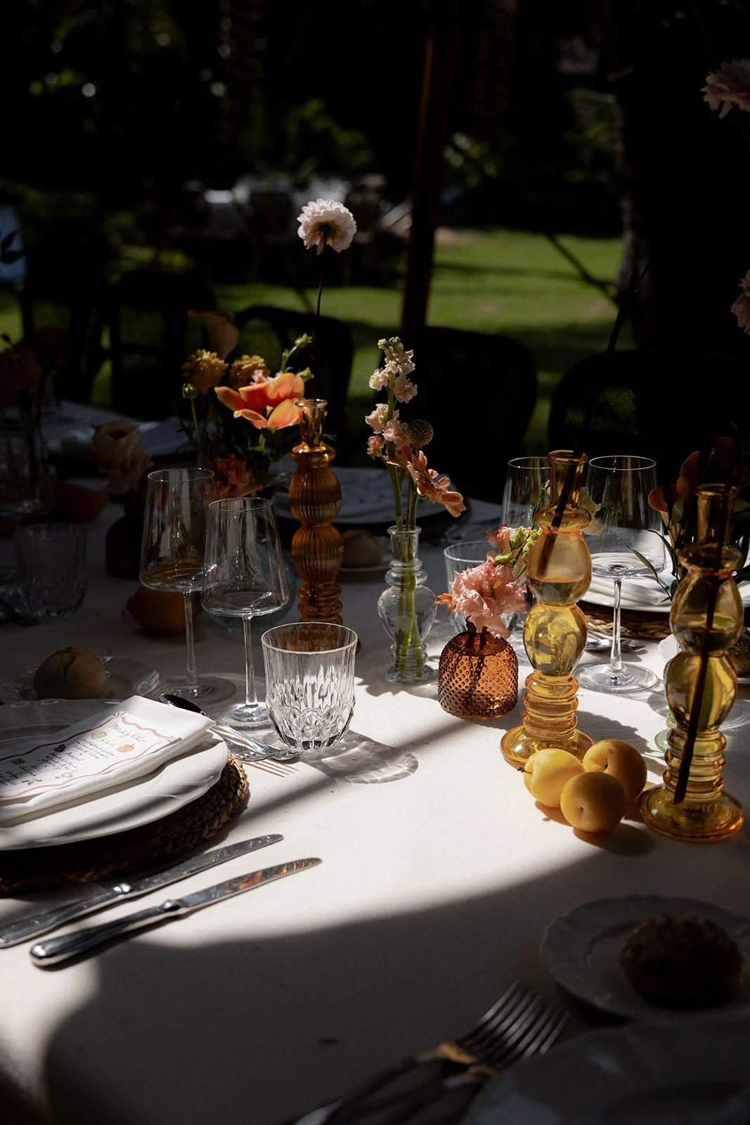 Primer plano de decoración floral y cristalería ámbar en la Finca El Molino del Duque en Manilva, Marbella bañada por la luz natural. Estilismo de mesa cuidado al detalle propio de bodas editoriales.