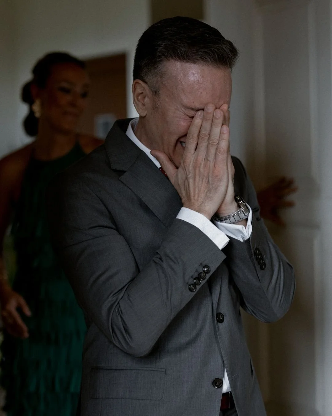 Padre de la novia cubriéndose el rostro emocionado al ver a su hija vestida de novia. Fotografía de boda sin posados que captura reacciones auténticas.