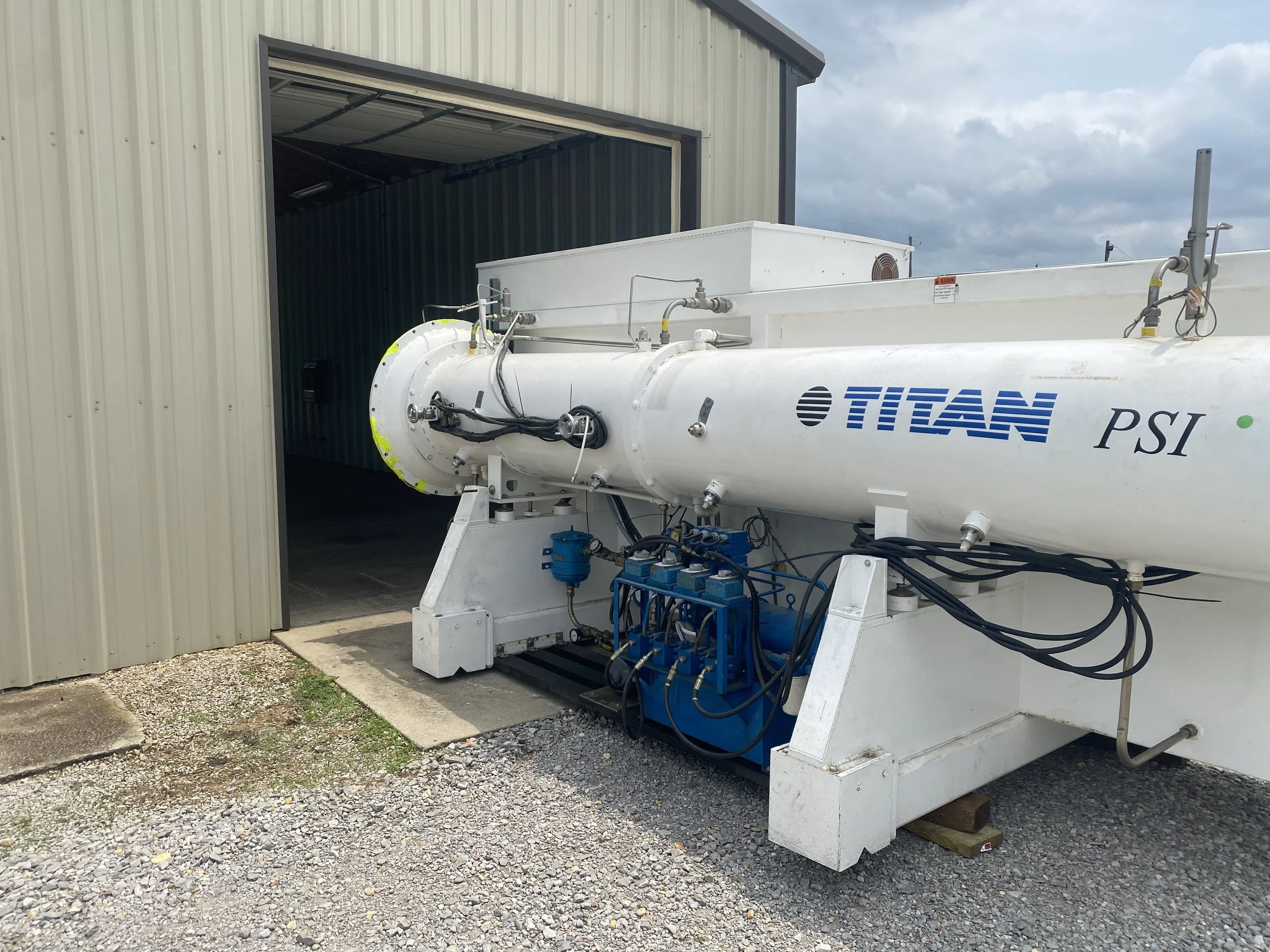 A large tube-shaped piece of equipment apparently outside of a garage-like structure.