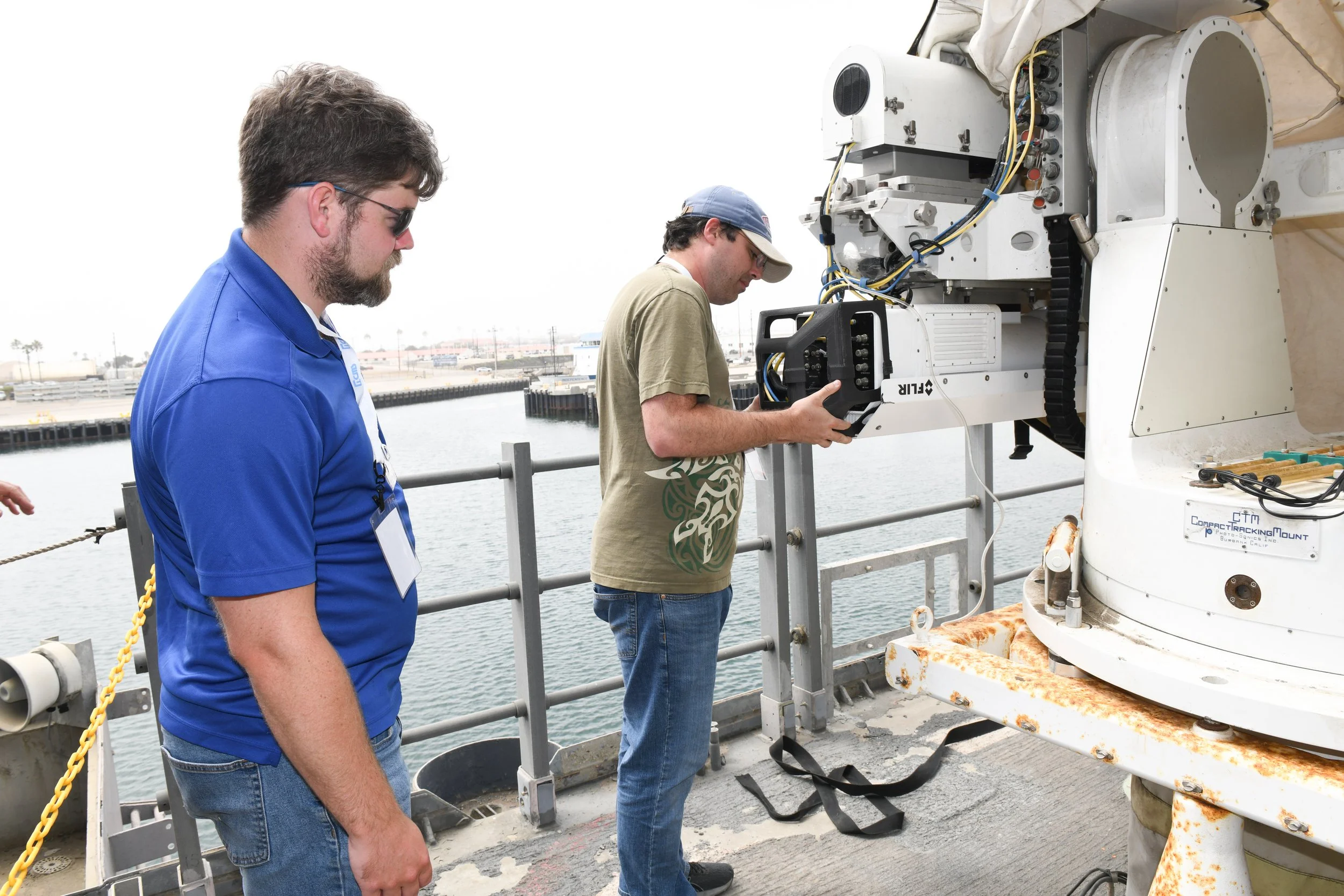 Two IS4S employees working on equipment on an outside ship deck.
