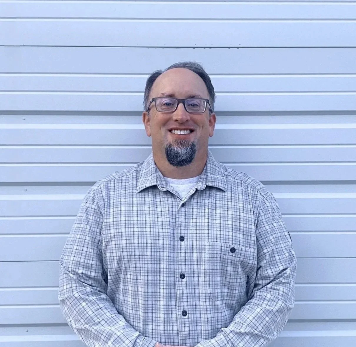 Man wearing glasses and a white shirt with 'Behnken Concrete LLC' logo, standing against white background.