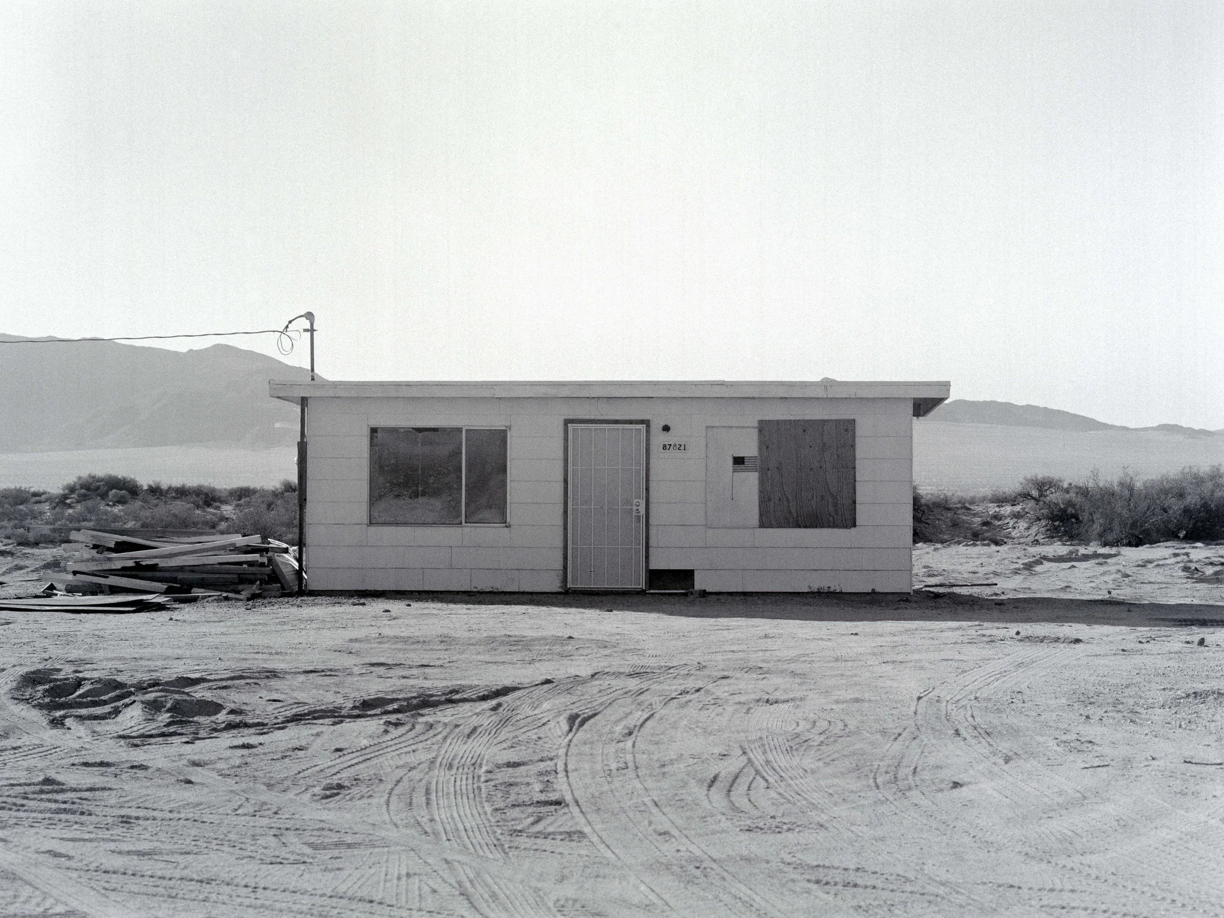 maison isolée en bord de désert avec vue sur des montagnes en arrière-plan