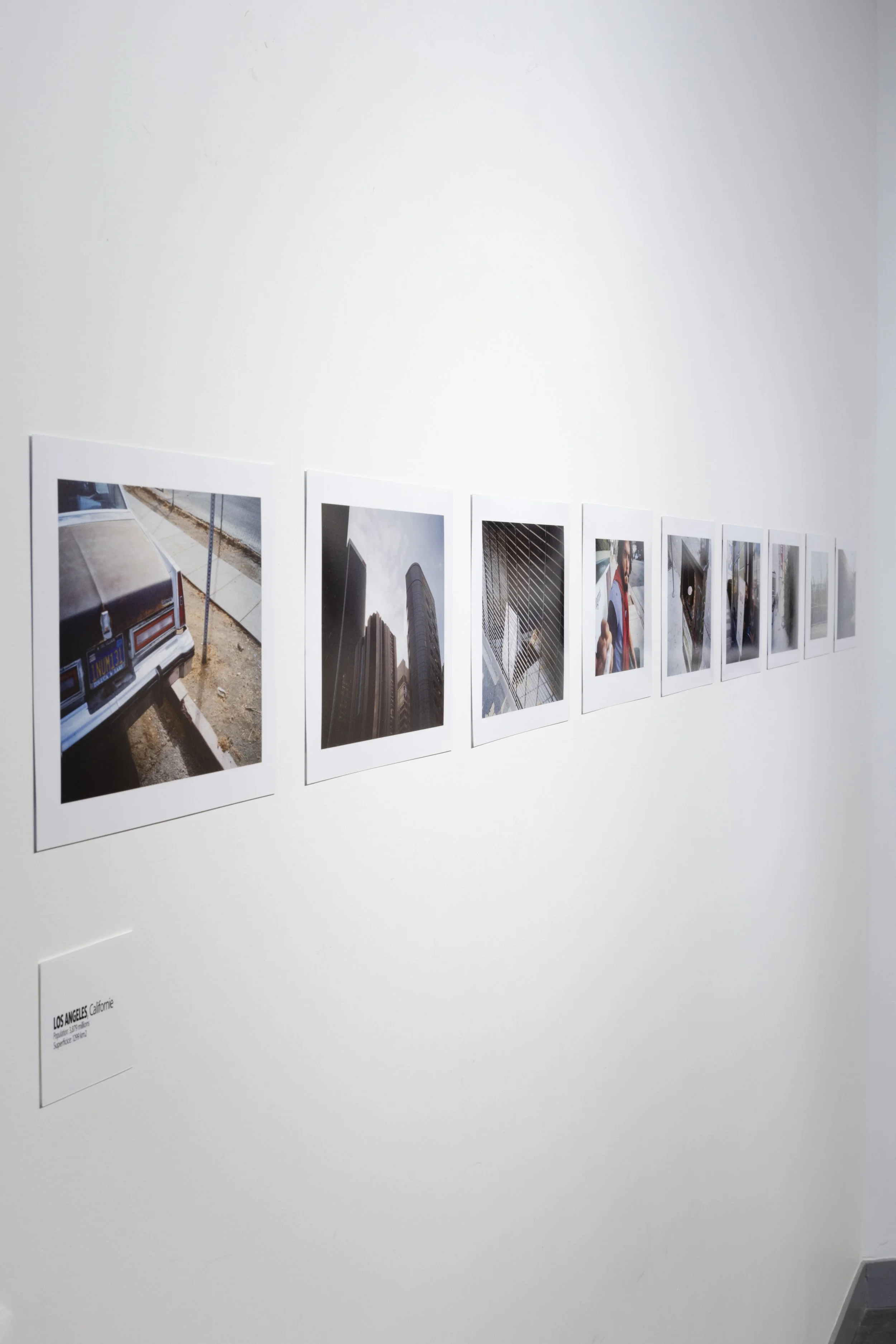 Une série de photographies polaroid accrochées à un mur blanc dans une galerie d'art, la légende indique 'LOS ANGELES Californie'.