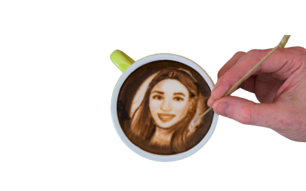 Hand creating latte art of a woman's face