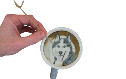 Hand creating latte art of a woman's face