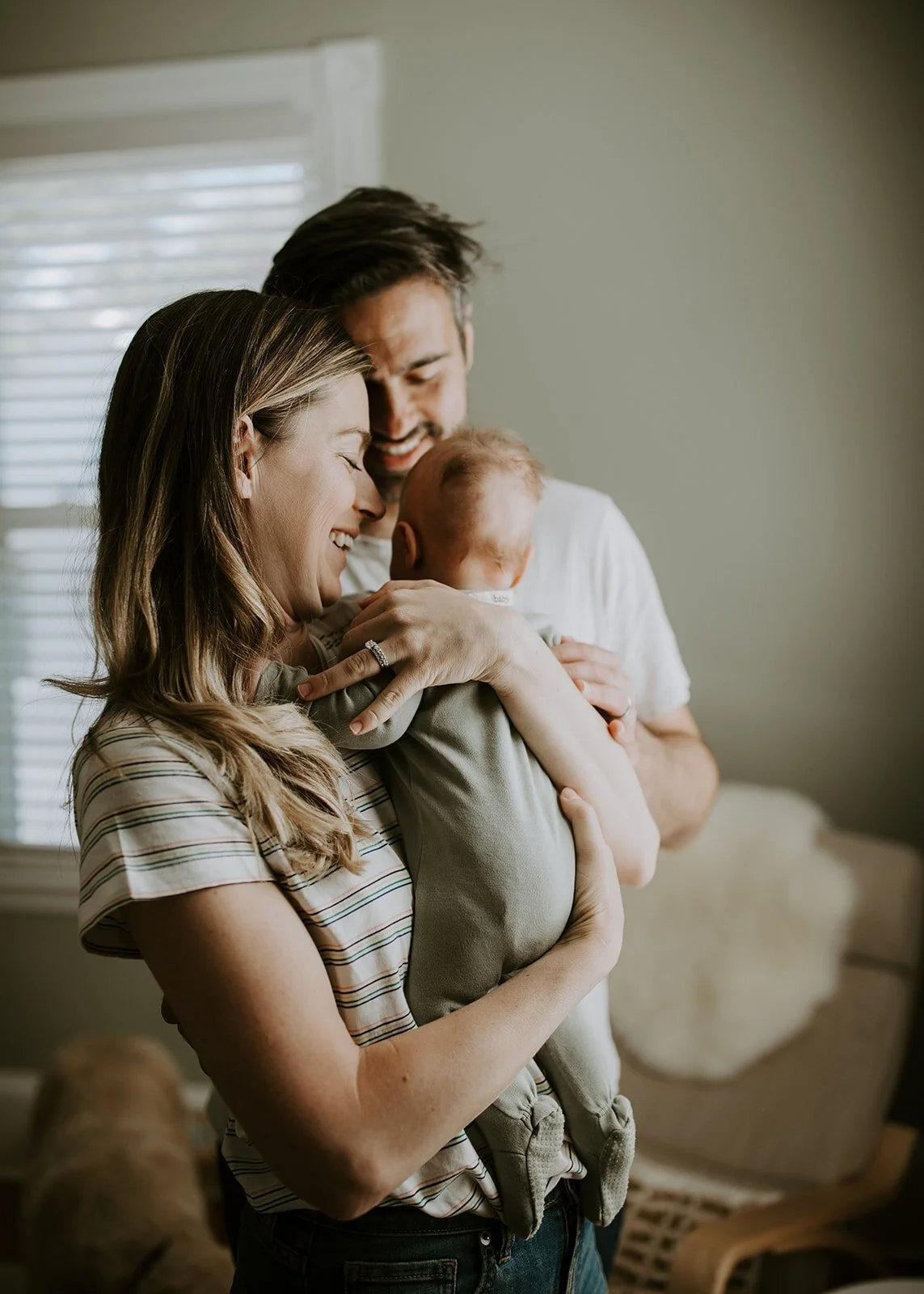 Man+and+woman+indoors+smiling+holding+baby.jpeg