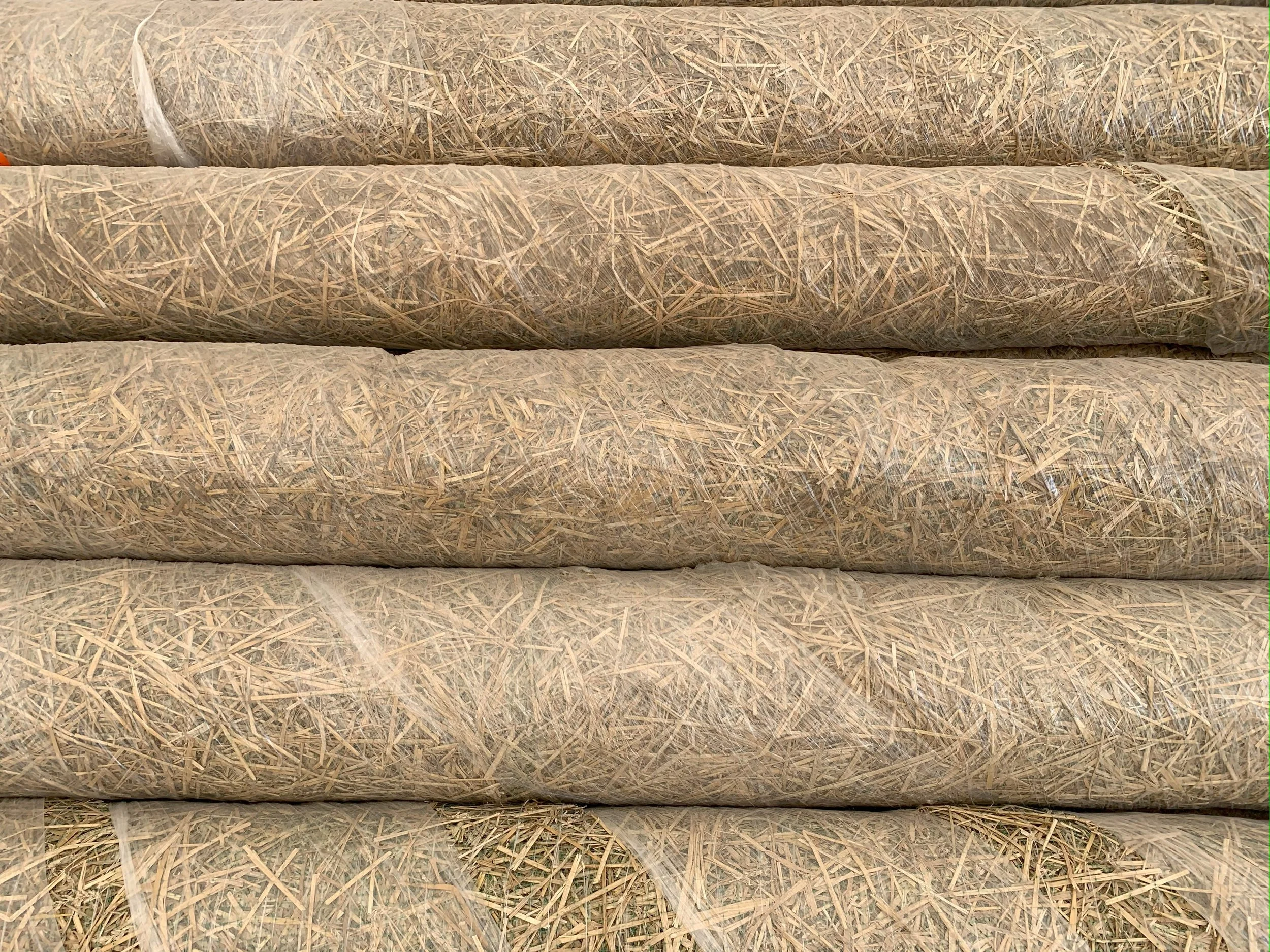 stacked rolls of straw under netting