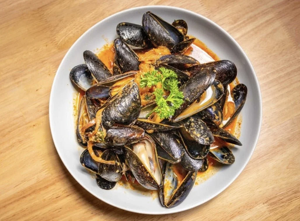 Close up of a hearty portion of Desotos famous fresh PEI Mussels in a spicy coconut Thai curry sauce