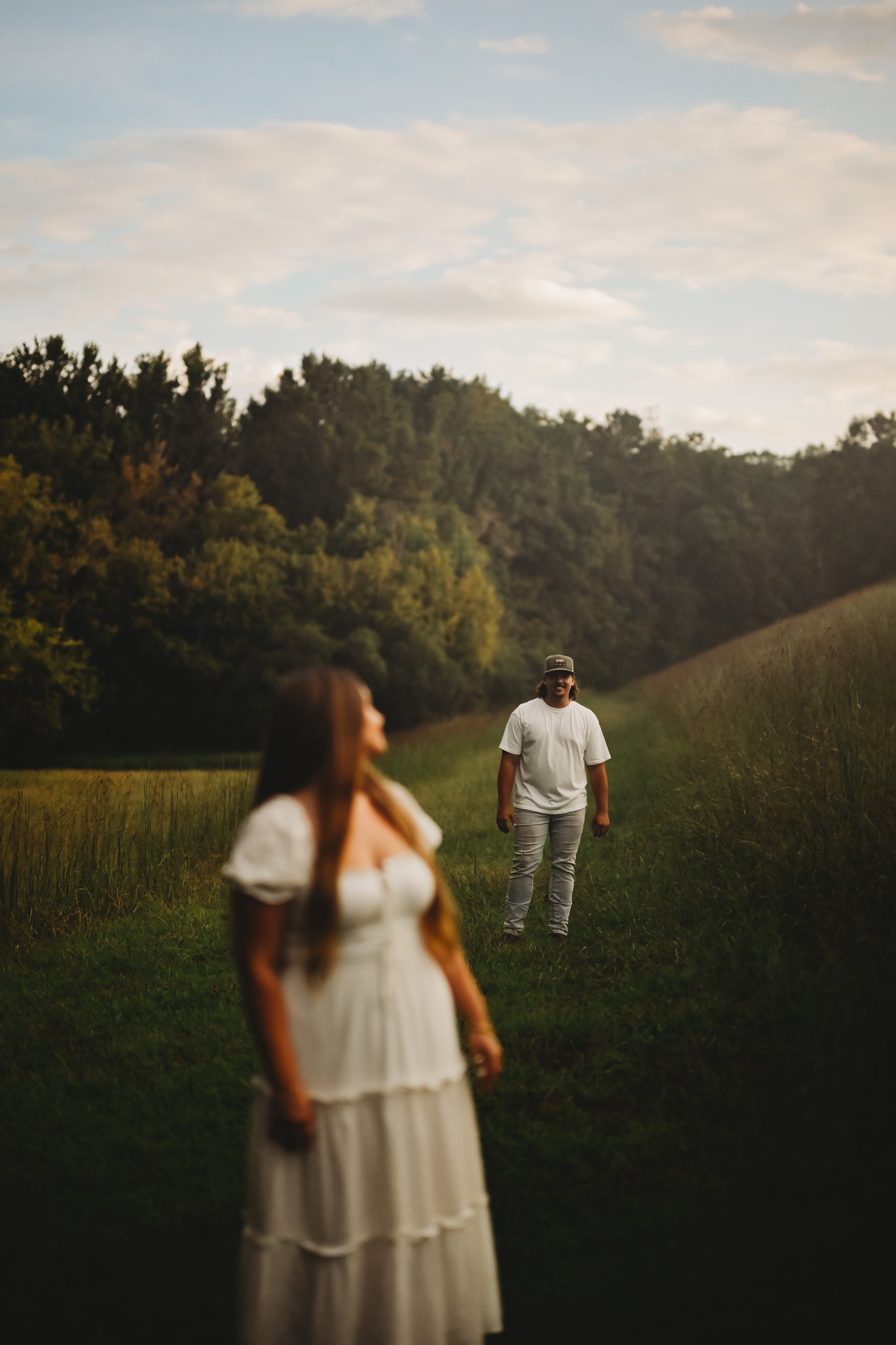 Candid lifestyle photography of a couple outdoors in a grassy field at golden hour.