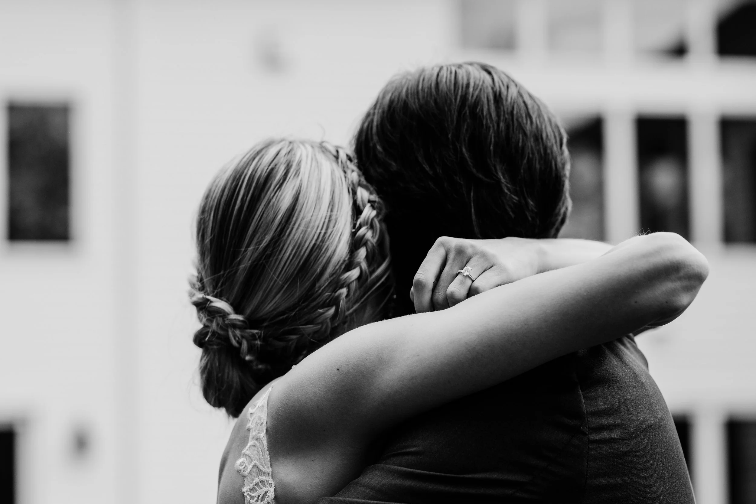 Candid black-and-white wedding photography capturing an emotional embrace.