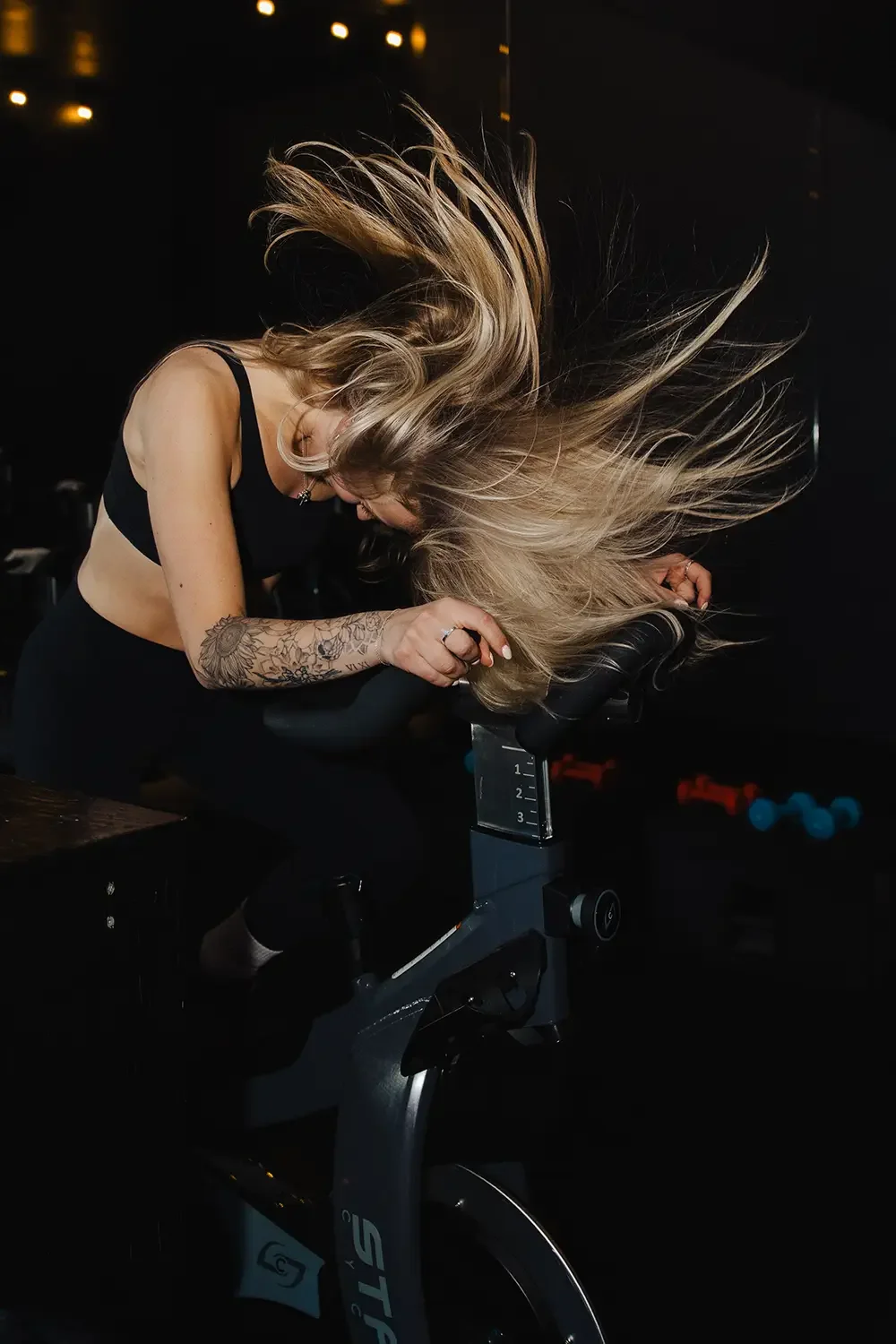 Action portrait of a woman on a spin bike flipping her hair