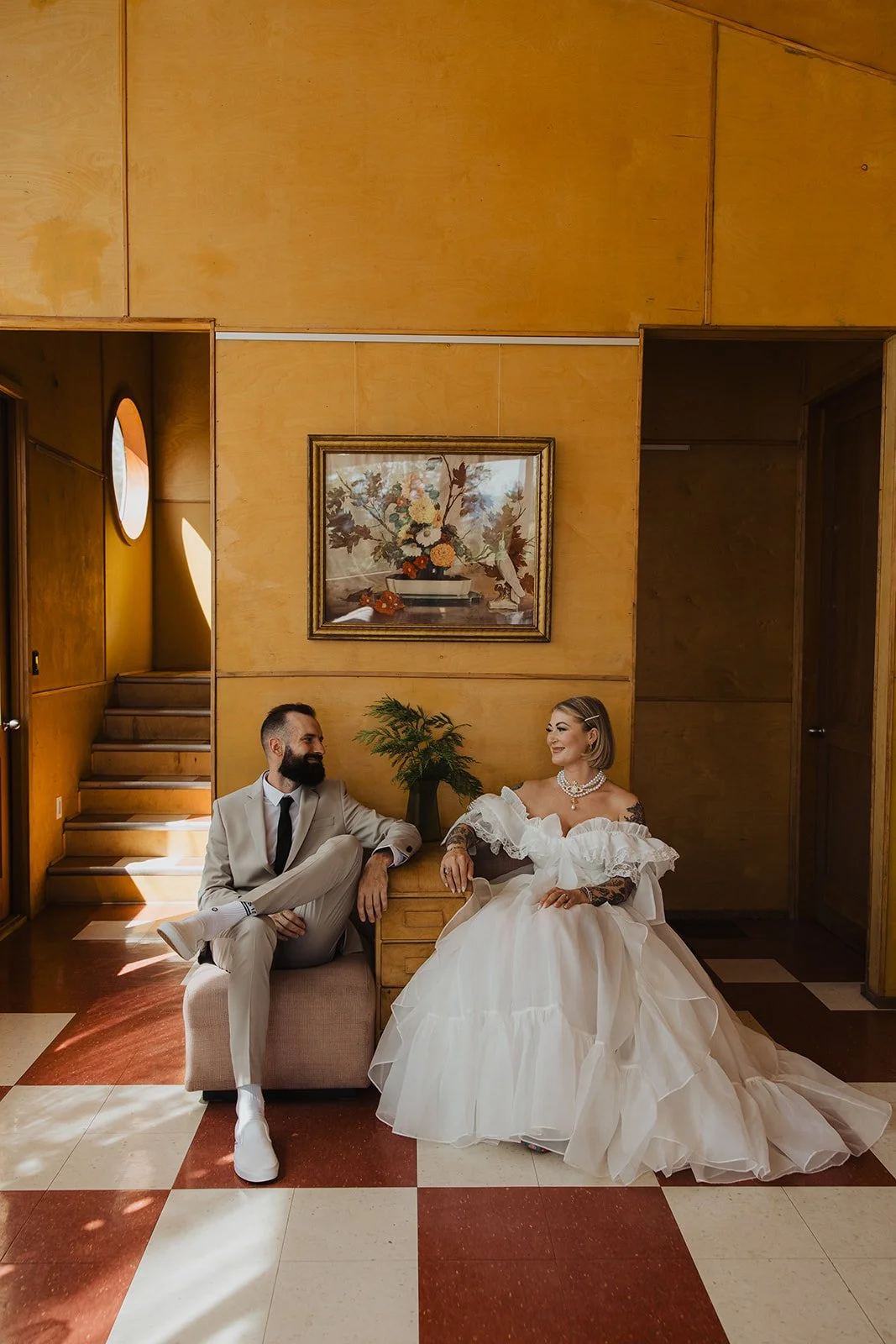 Bride and groom seated in a mid-century room on their wedding day