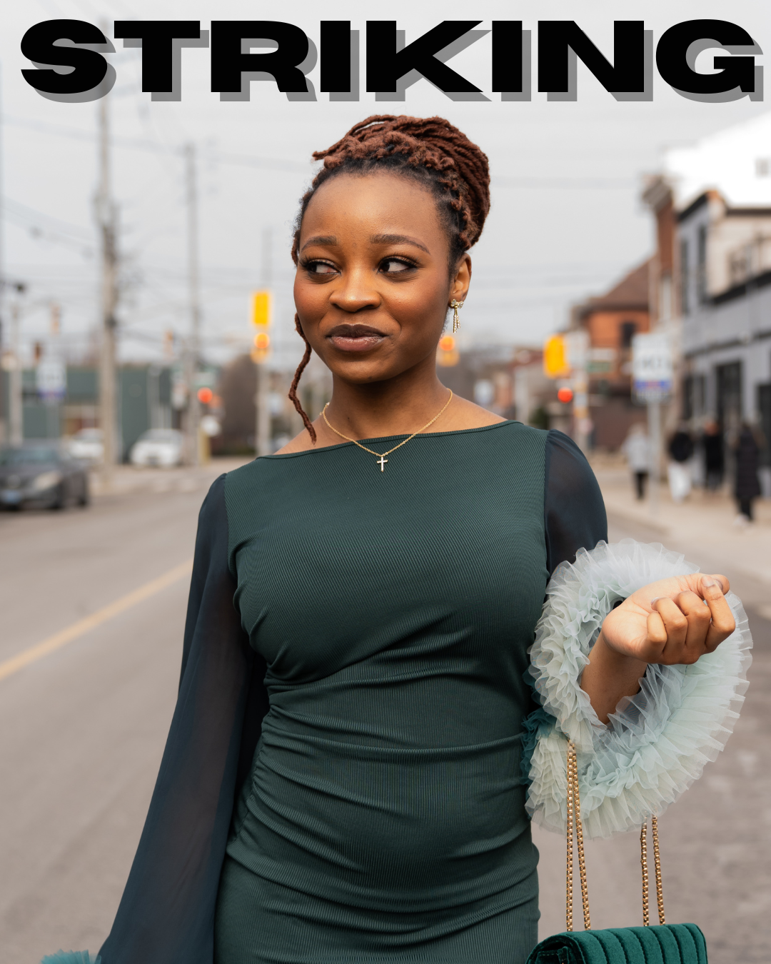 A young woman standing outside on a city street, looking to her left, with a confident expression. She is wearing a dark green dress with sheer black sleeves, gold jewelry, and is holding a purse with ruffled detailing. The word 'STRIKING' is displayed in large black letters at the top of the image.