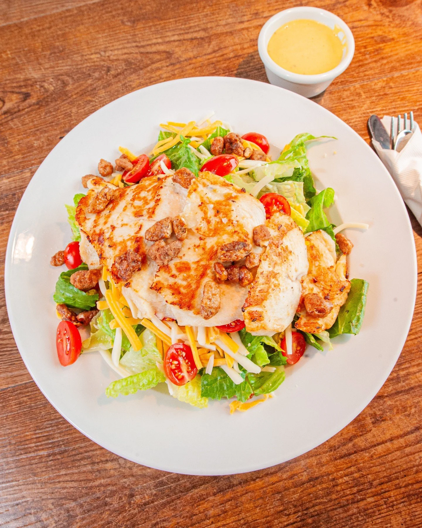 Add a little sunshine to your day with our new Grilled Chicken Pecan Salad! Juicy grilled chicken, sweet glazed pecans, grape tomatoes, and cheddar jack cheese come together over crisp romaine with honey mustard dressing on the side.
