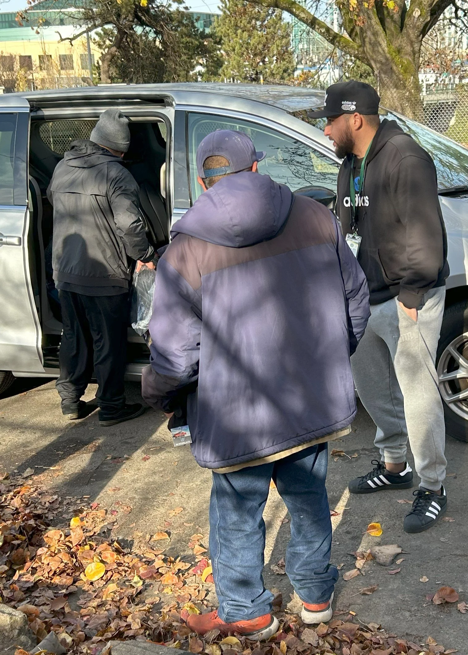 Two Harm reduction specialists make a harm reduction bag for a houseless individual. They are meeting outside a van, speaking about recovery services
