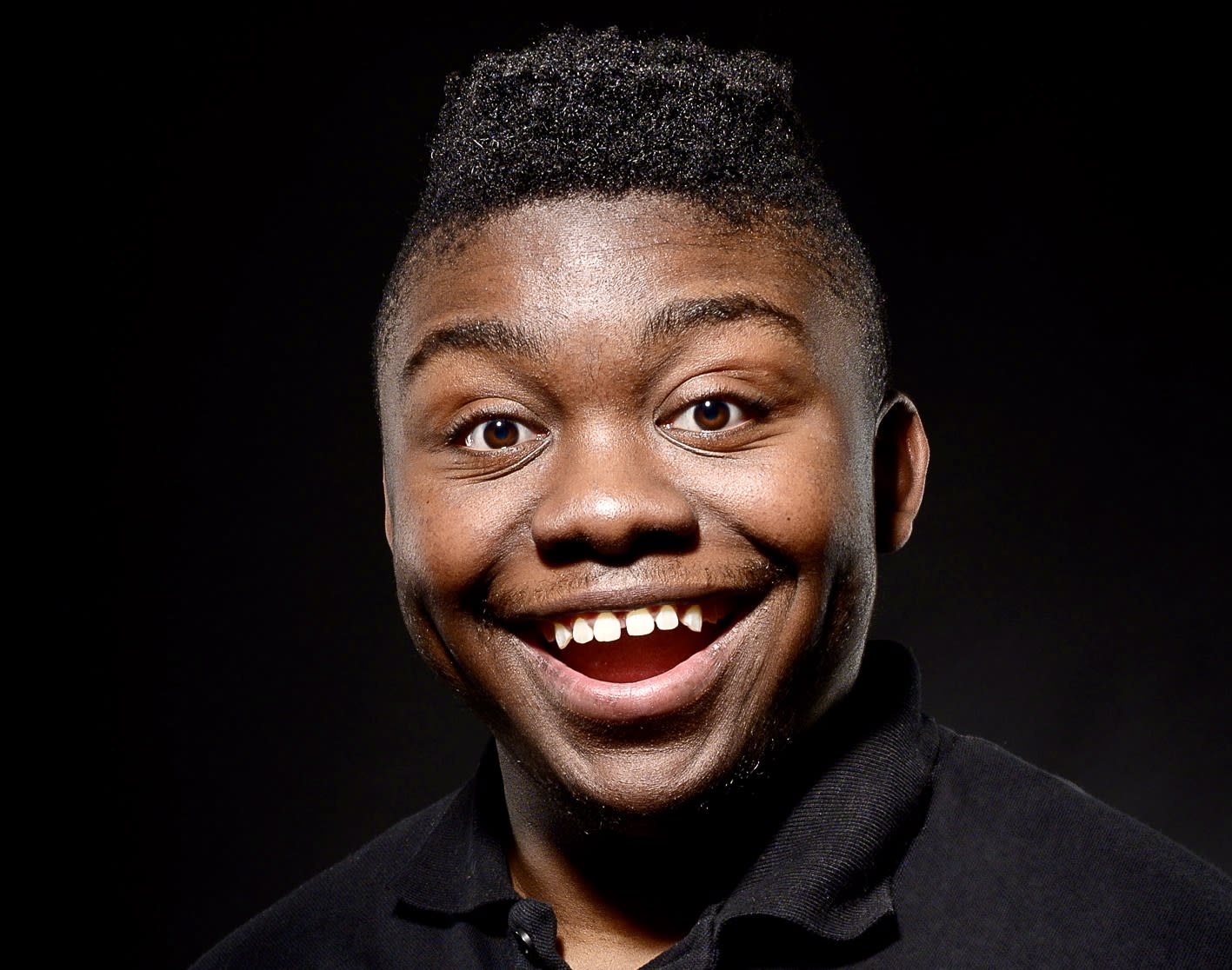 Smiling person in a black shirt on a black background